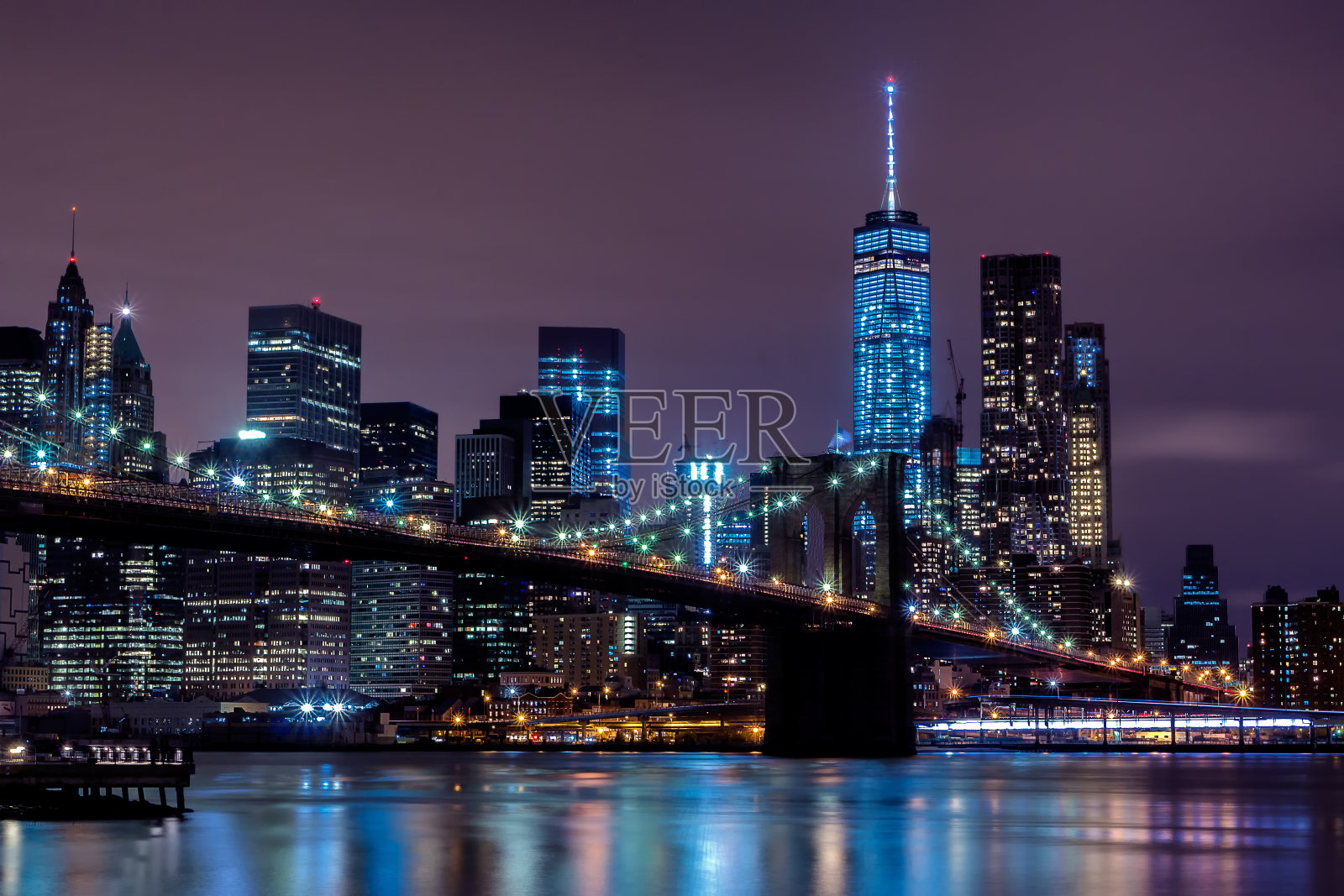 夜晚，灯火通明的建筑和布鲁克林大桥映衬着天空照片摄影图片