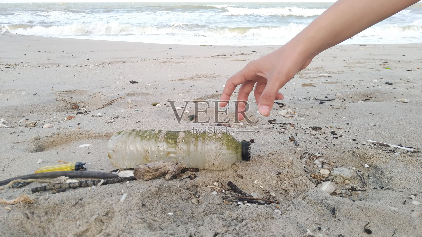 在海滩捡垃圾的人的裁剪手照片摄影图片