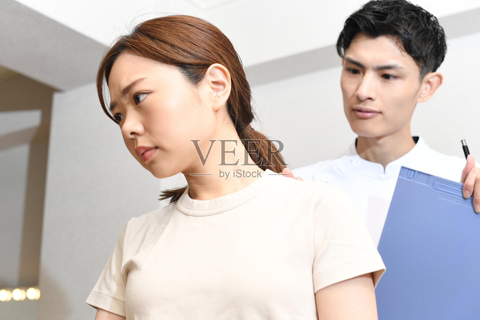 亚洲男性脊医或物理治疗师为检查女性病人的身体状况而进行按摩治疗照片摄影图片