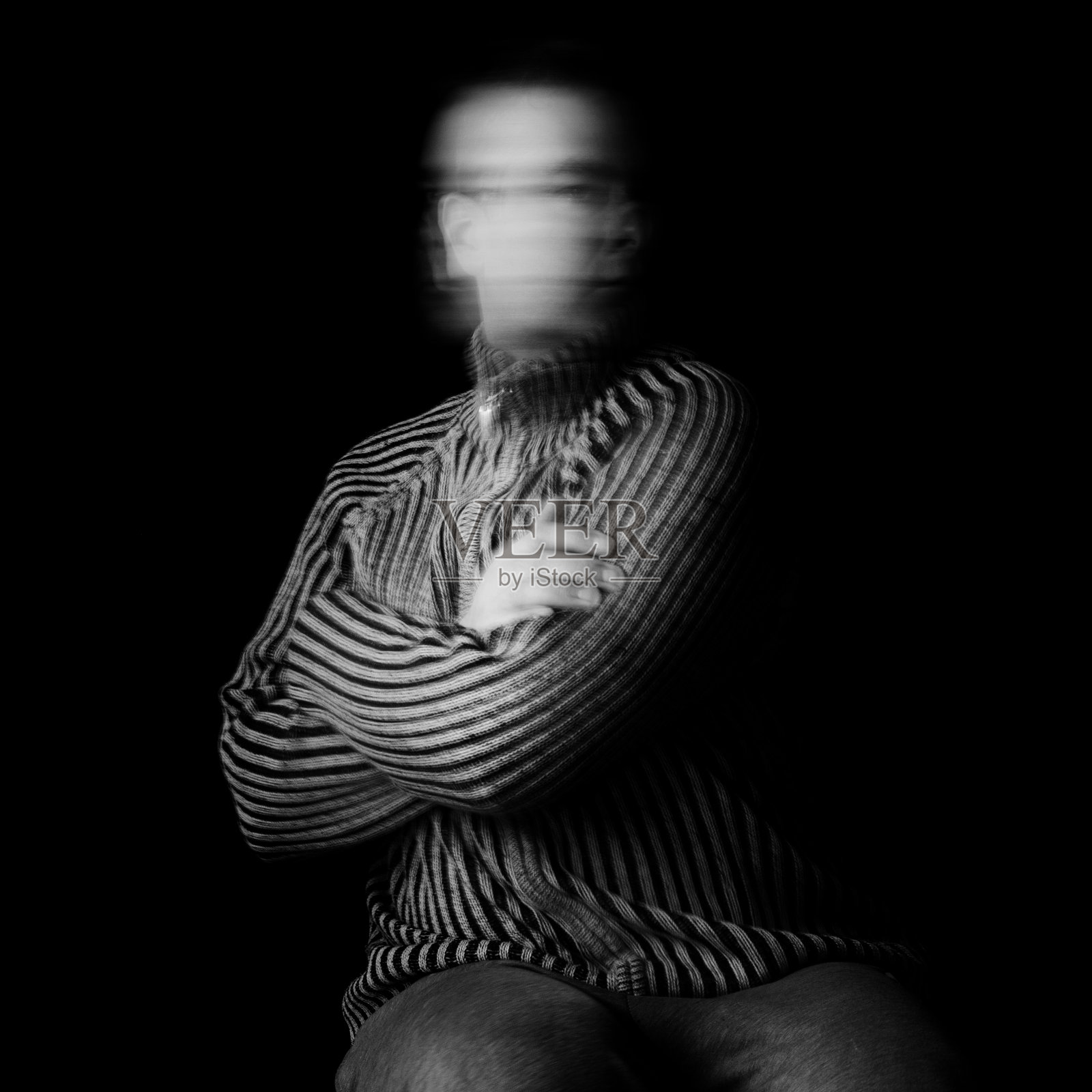 男子在黑色背景下双手交叉坐着时摇头照片摄影图片