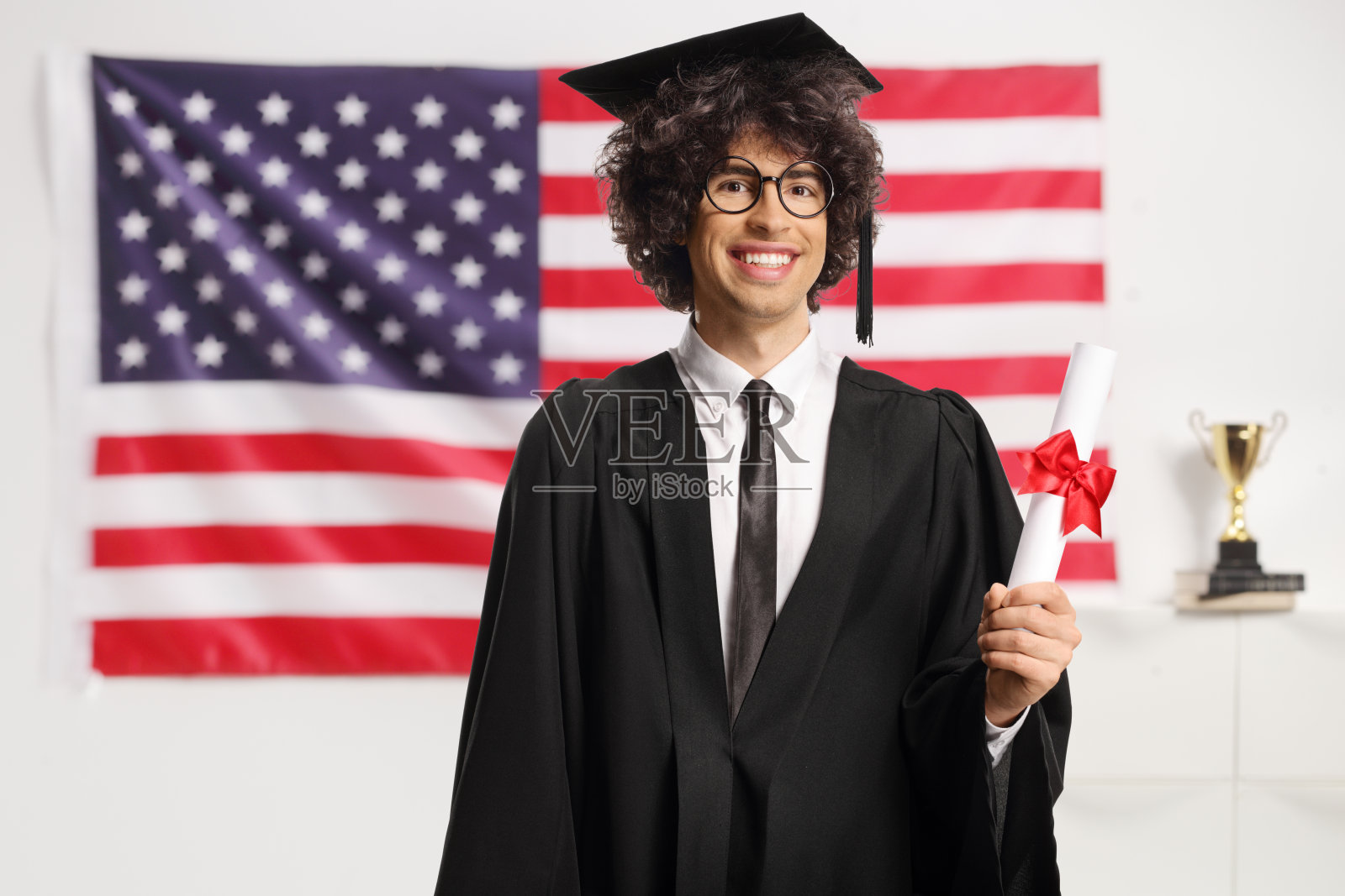 男学生戴着眼镜，穿着毕业礼服，拿着毕业证书照片摄影图片