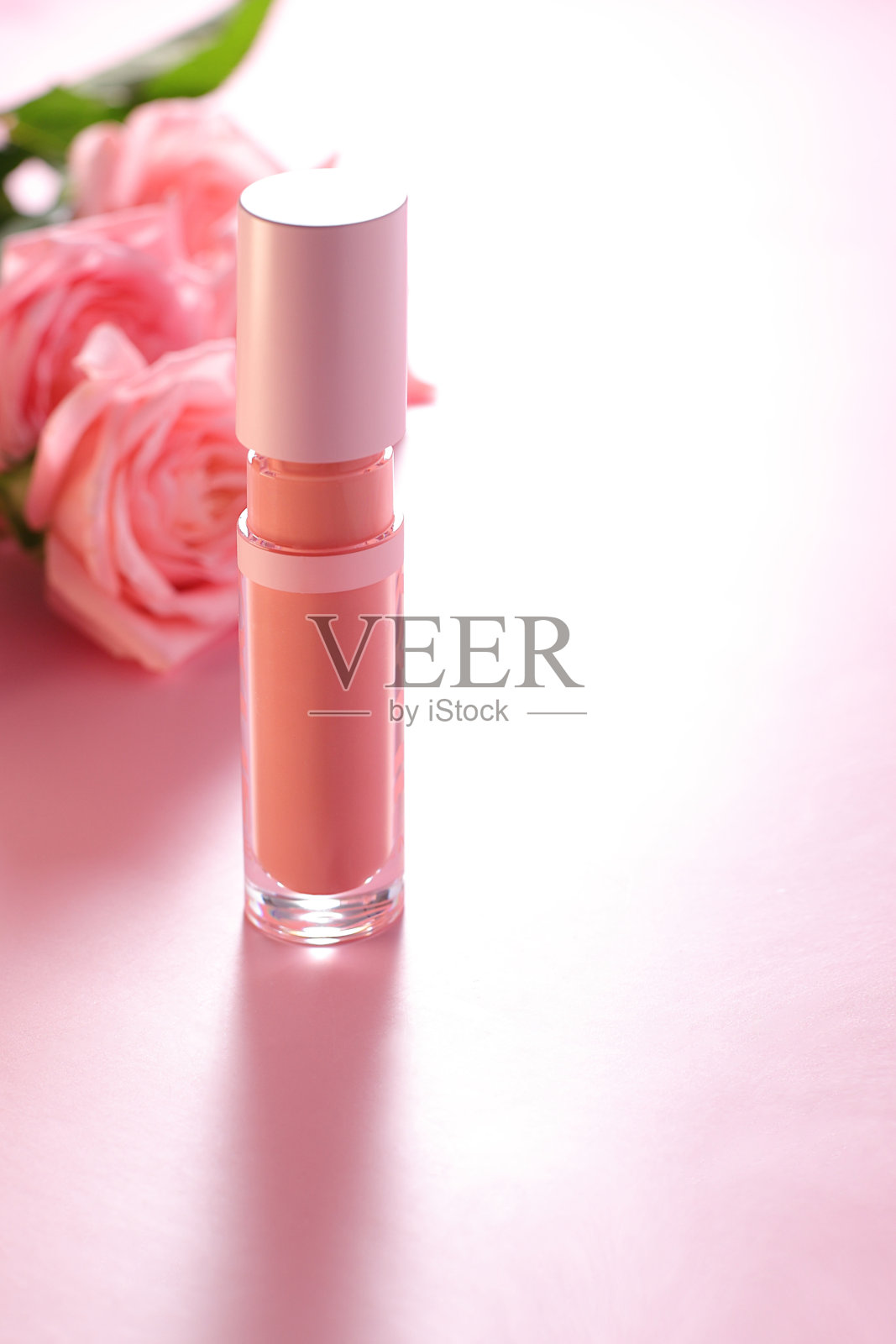 裸色米色唇彩管与玫瑰背景，化妆概念照片摄影图片