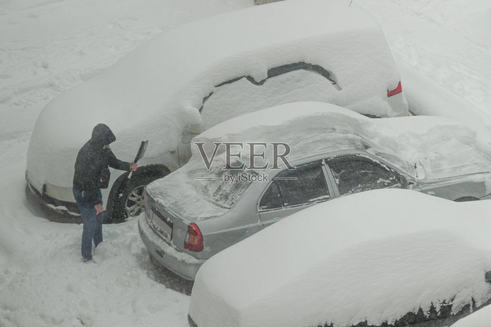 一个人在车上刷雪。城市里一个多雪的冬天照片摄影图片