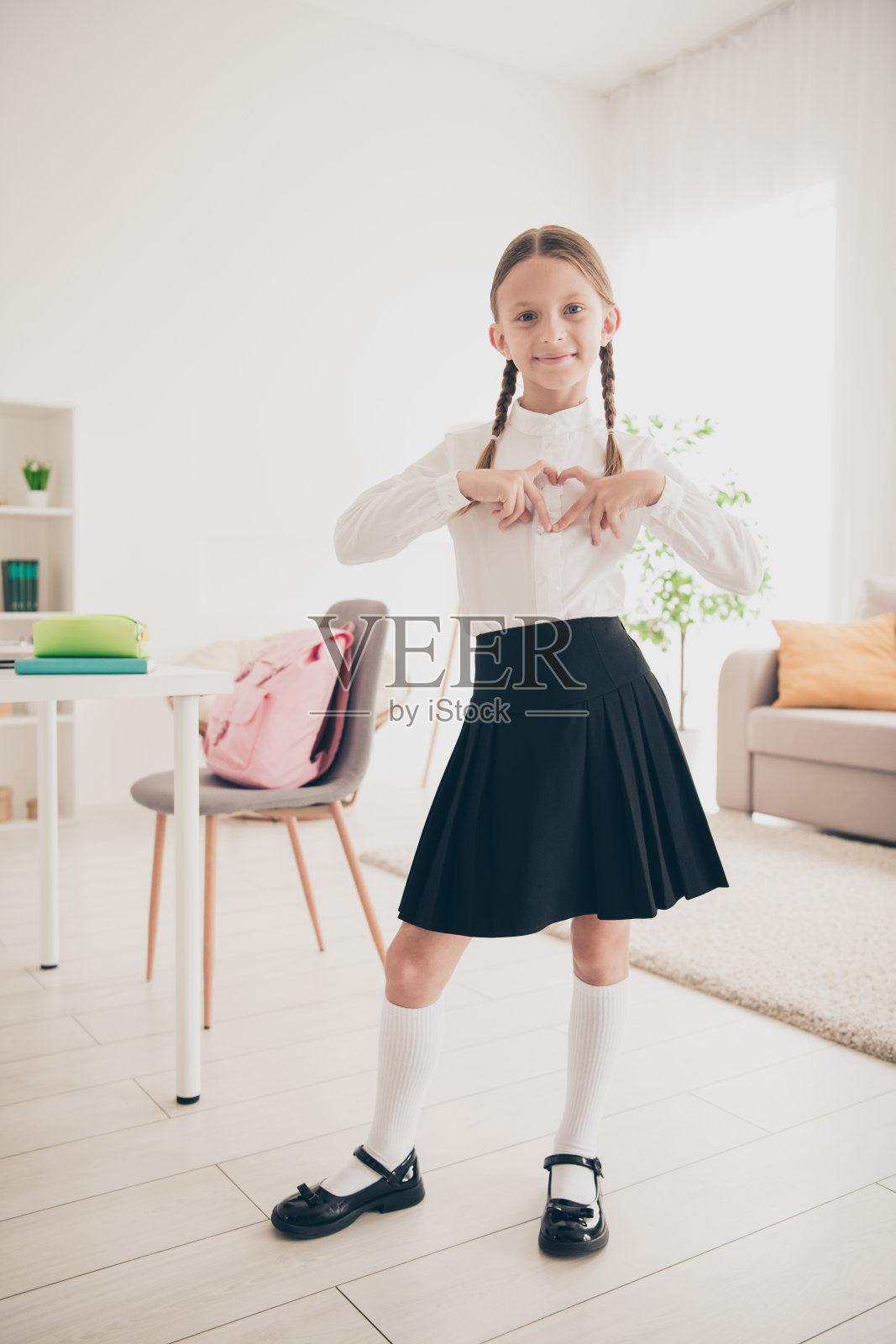 垂直照片可爱的小学生展示心穿统一的客厅公寓室内照片摄影图片