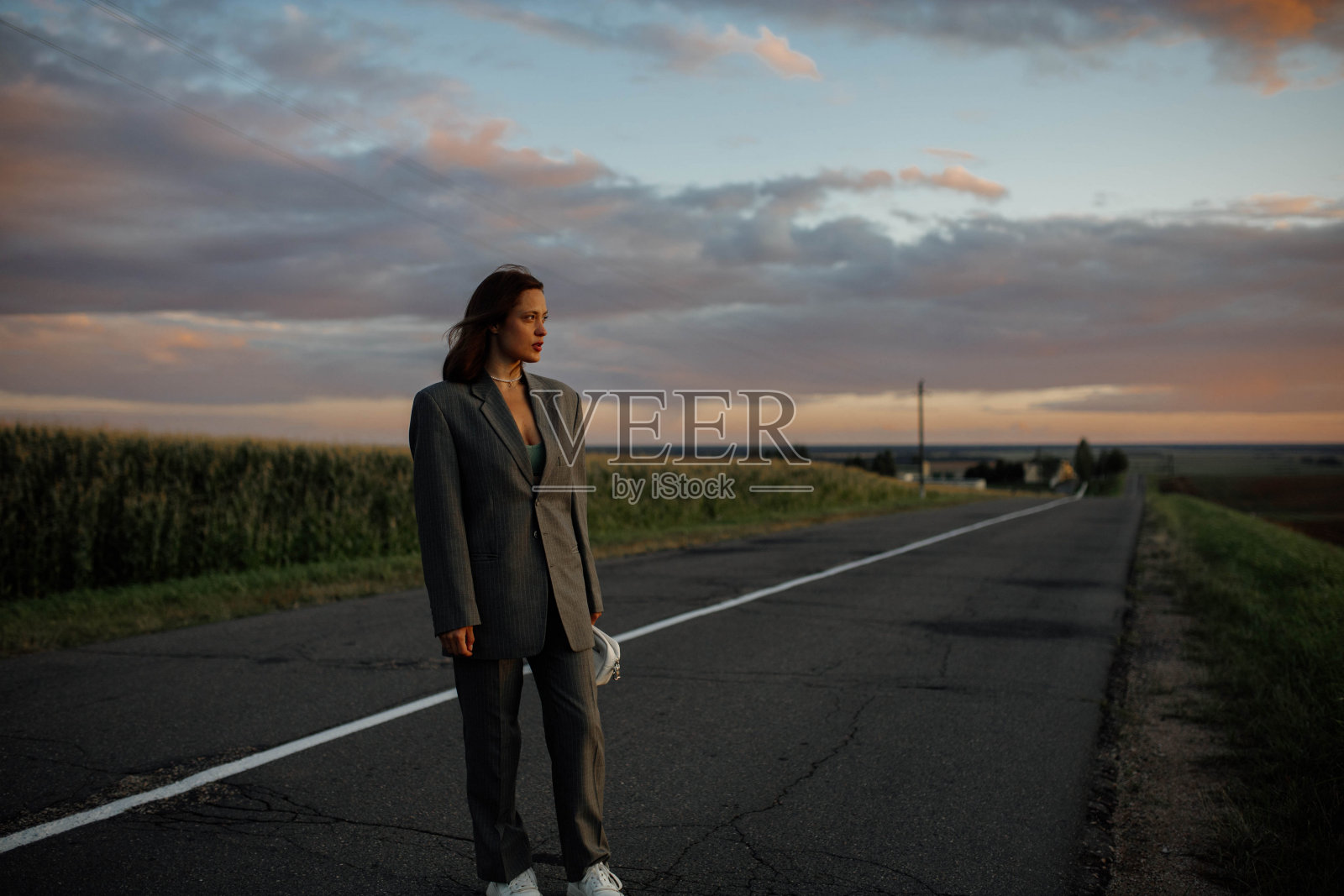 夕阳西下，一位身着西装的女士走在路上，职业危机照片摄影图片