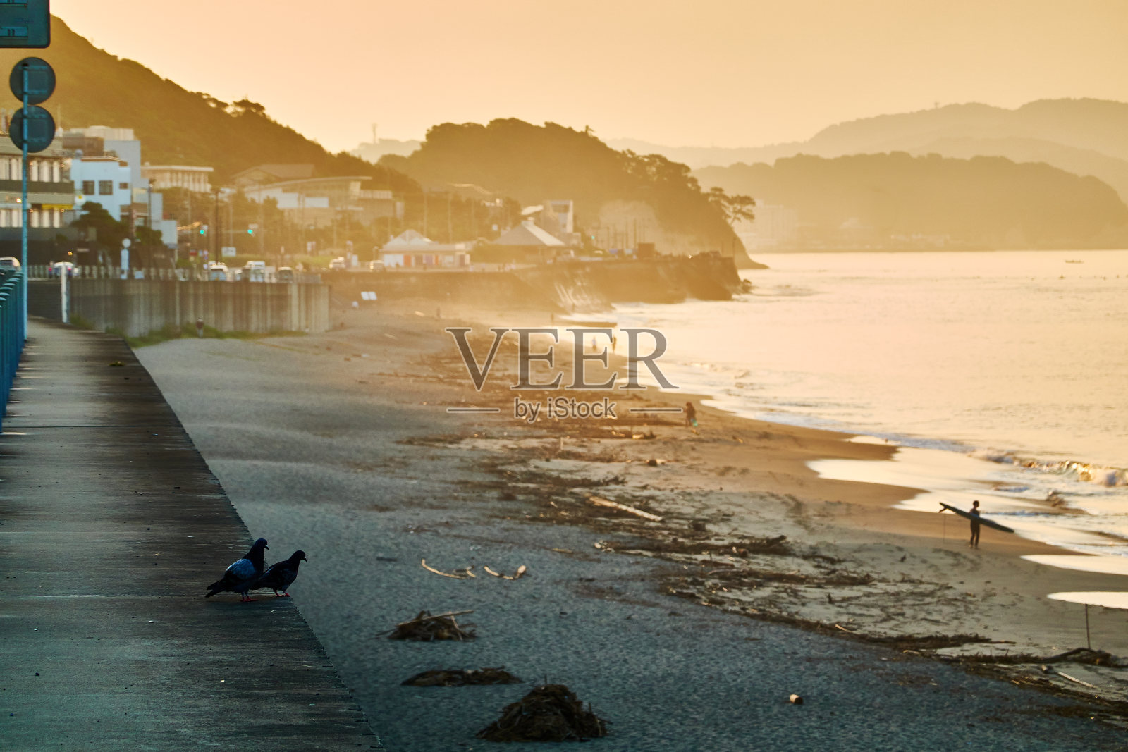 日出时，海滩风景优美，人们的身影映衬着喜怒无常的天空照片摄影图片
