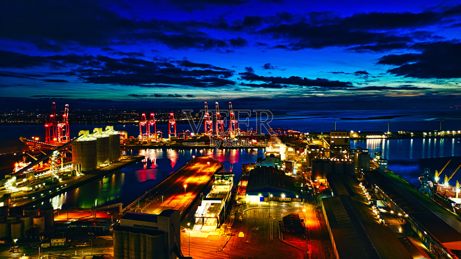 熙熙攘攘的港口夜景，灯火通明的起重机和建筑物照片摄影图片