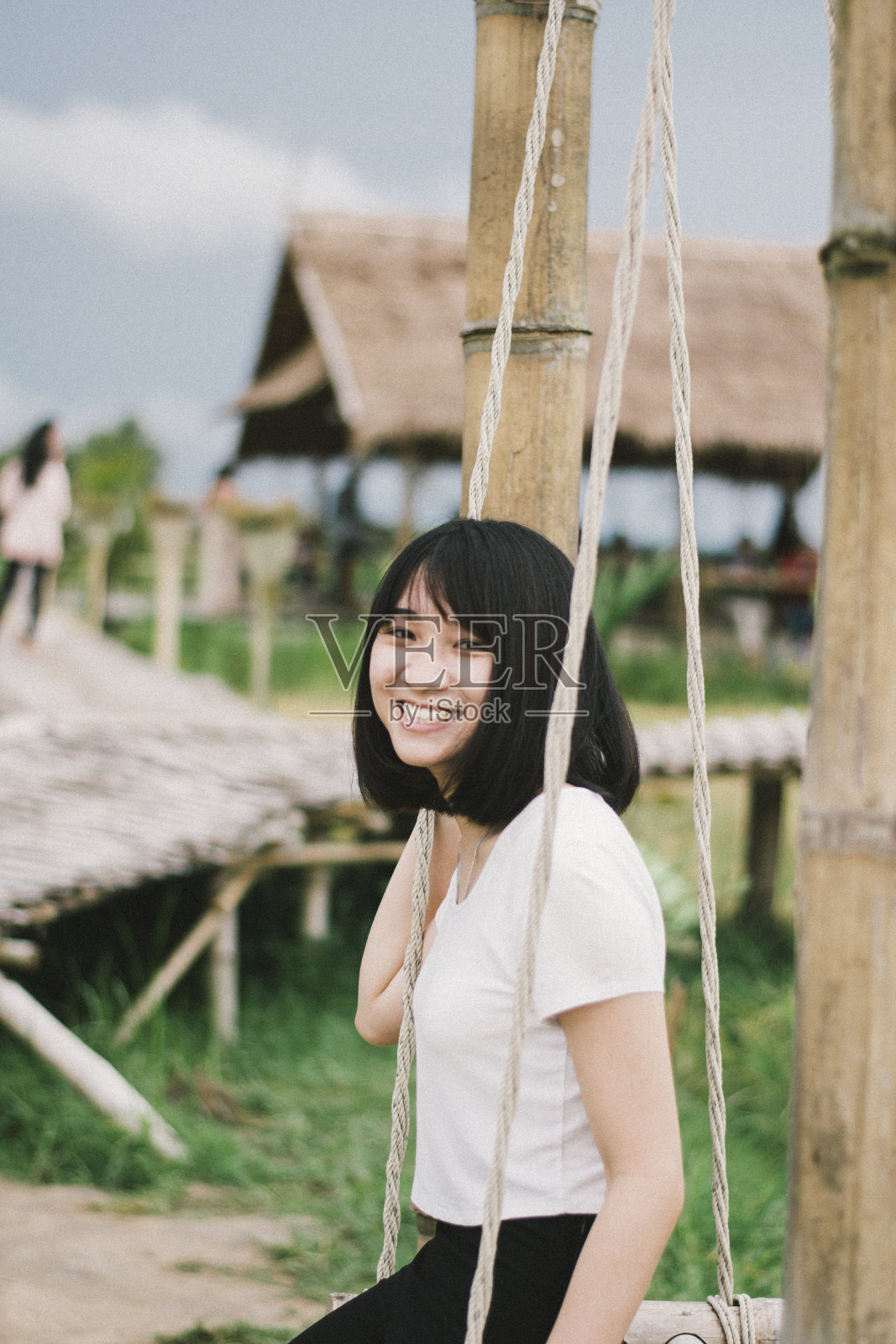 微笑的年轻女子坐在秋千上的肖像照片摄影图片