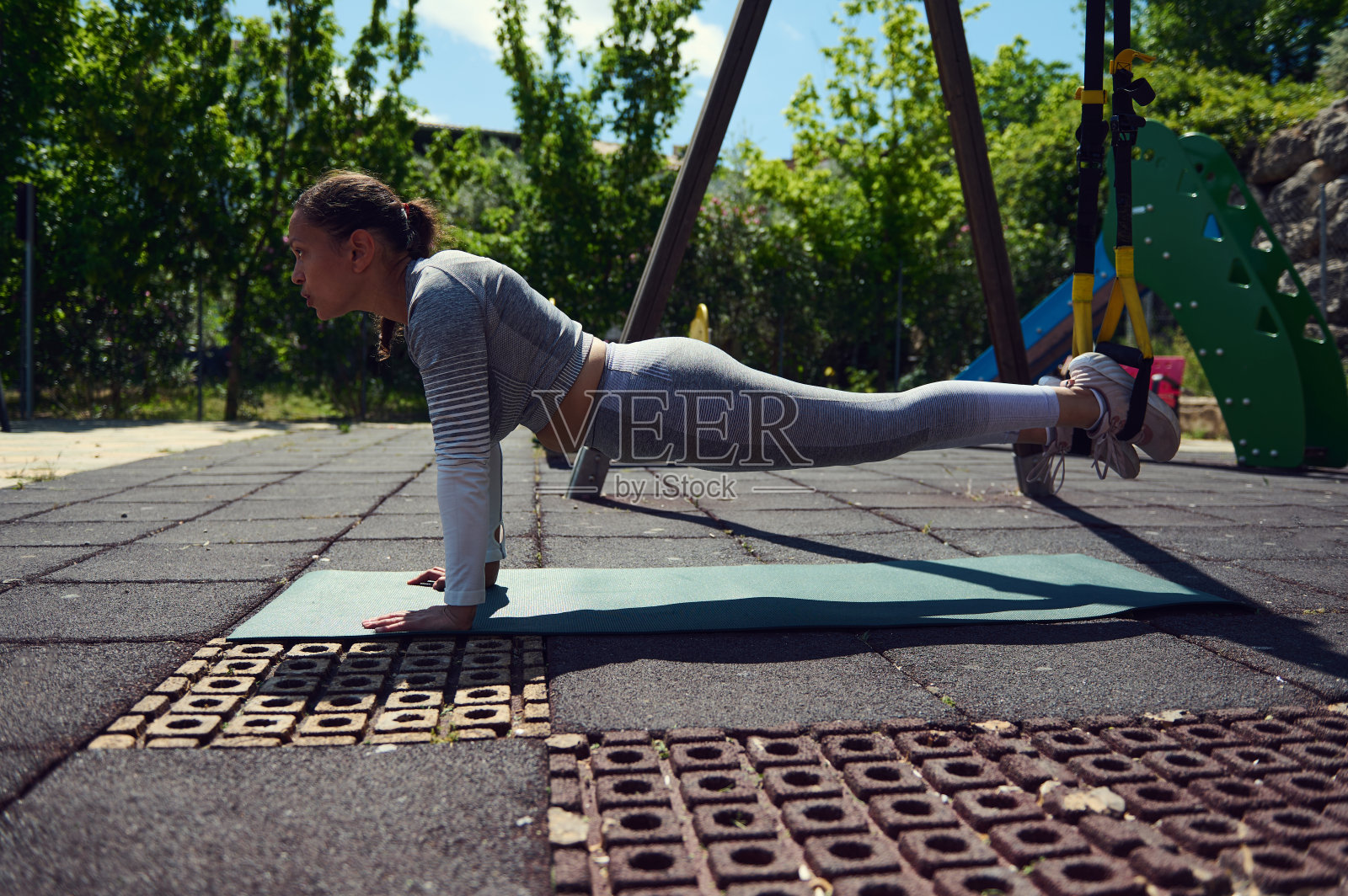 在公园的垫子上做平板支撑的女性，强调在阳光明媚的日子里的力量、健康和身体平衡照片摄影图片