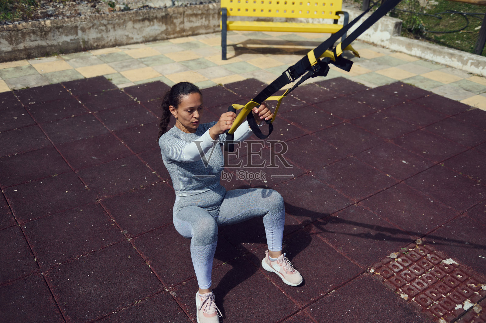 女人在阳光明媚的公园里进行TRX悬挂训练照片摄影图片