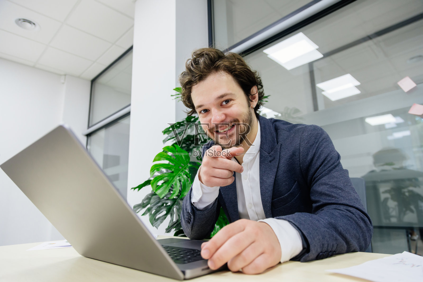 在一间现代化的办公室里，一位留着胡子的年轻交易员正专注于他的笔记本电脑。非常适合展示金融和贸易活动。照片摄影图片