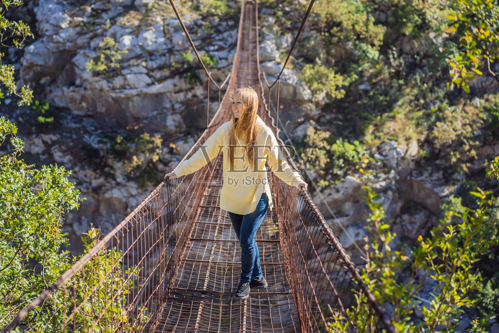 女游客在锈迹斑斑的老桥上。景点:横跨莫卡河的超长悬索桥。黑山的风景。具有里程碑意义的黑山照片摄影图片