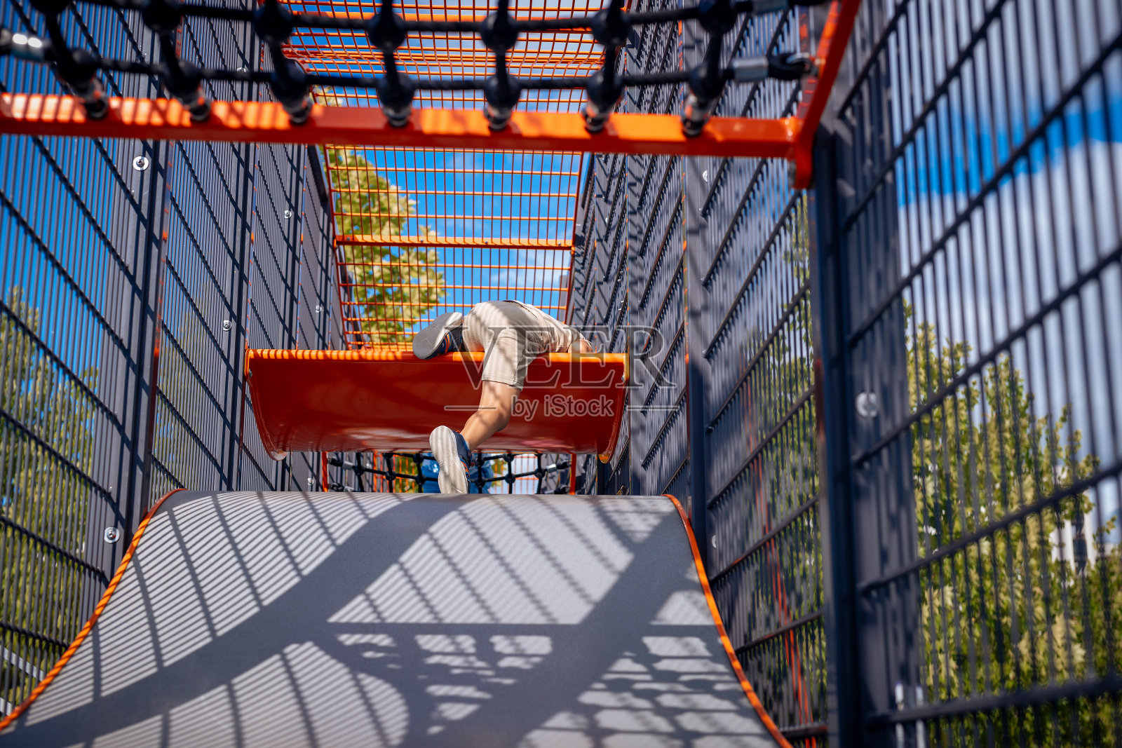 一个快乐的孩子在五颜六色的游乐场设备上热情地玩耍，展示了纯粹的乐趣和冒险。照片摄影图片