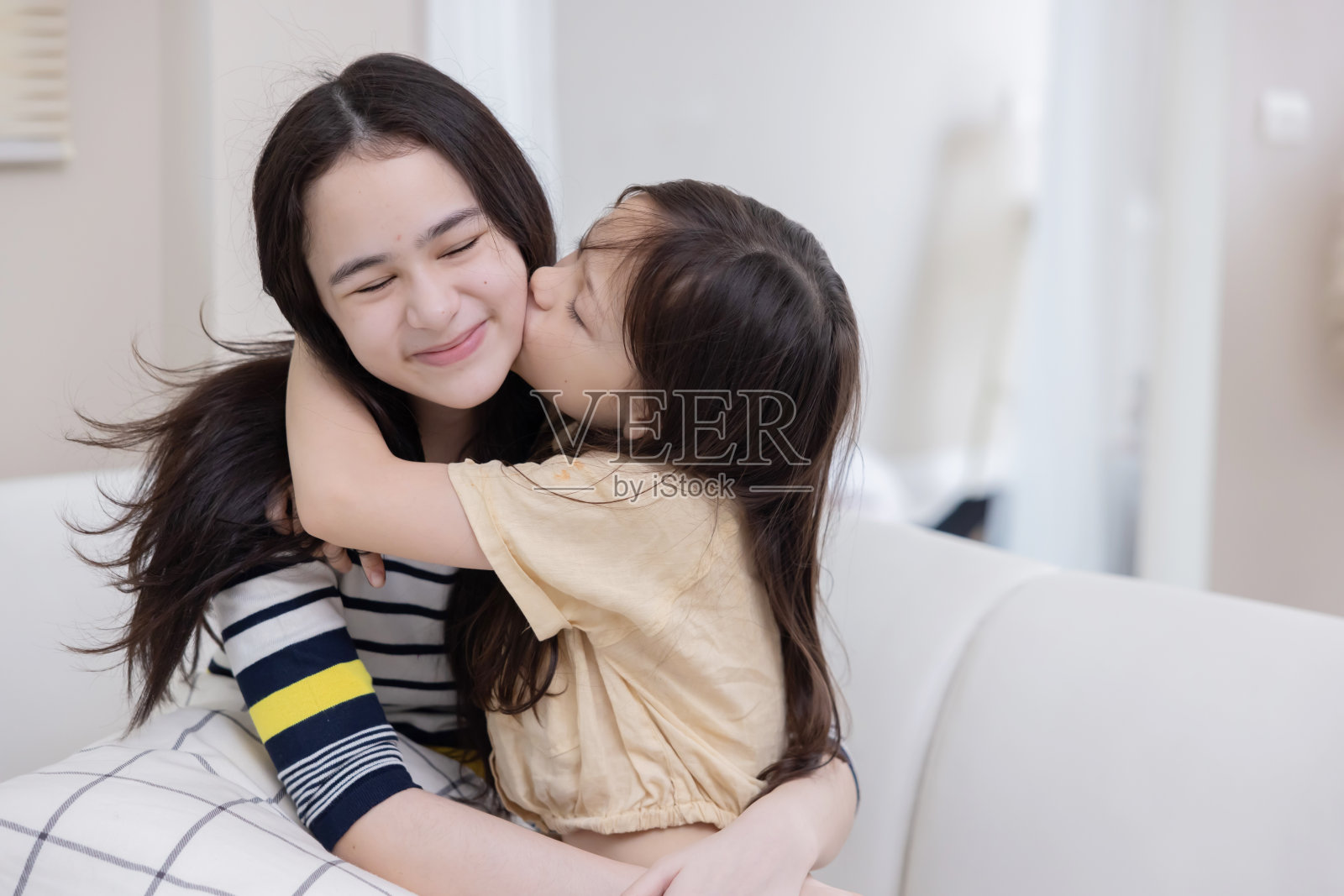 两姐妹在沙发上深情相拥照片摄影图片