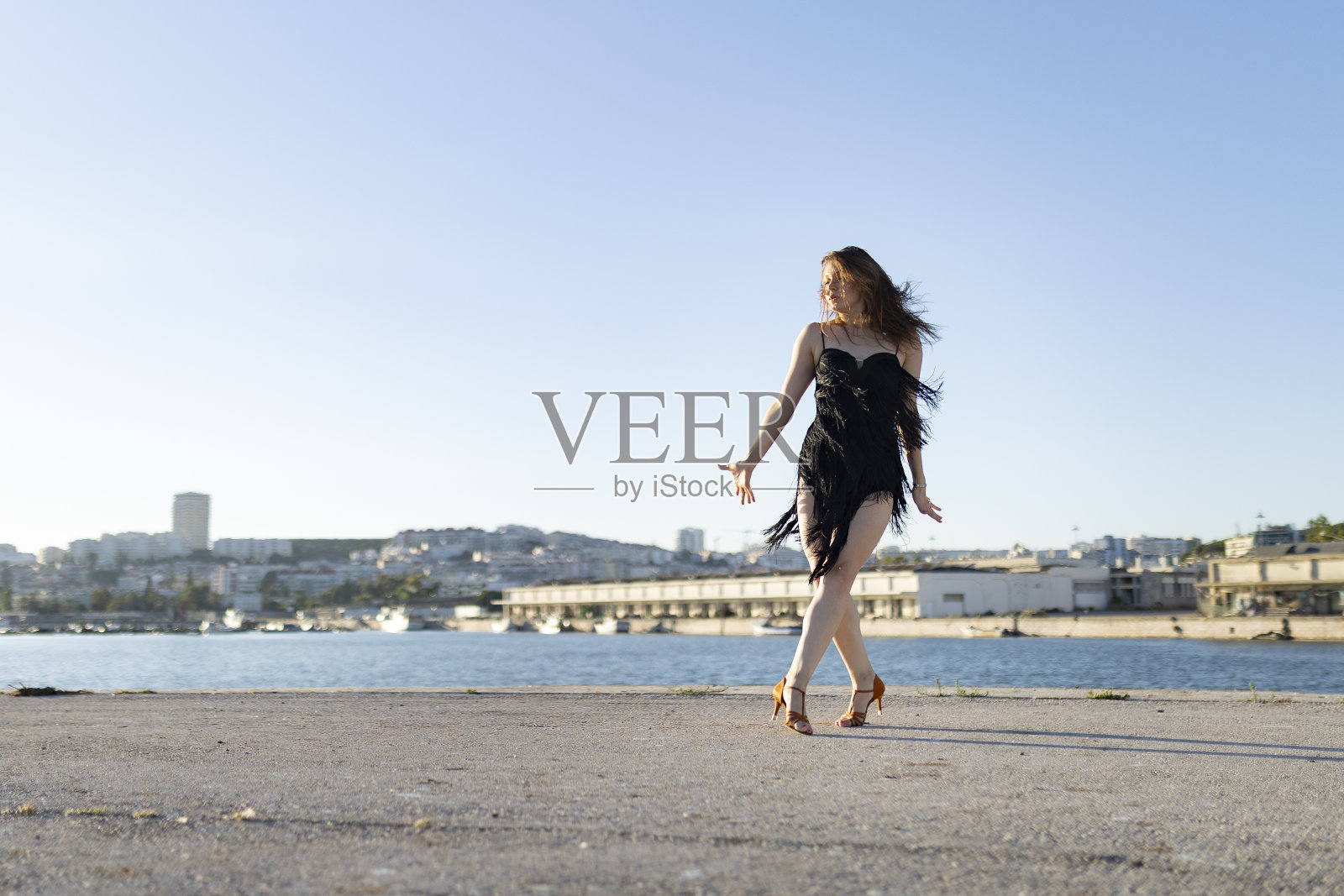 年轻女子在码头跳拉丁舞，背景是城市照片摄影图片