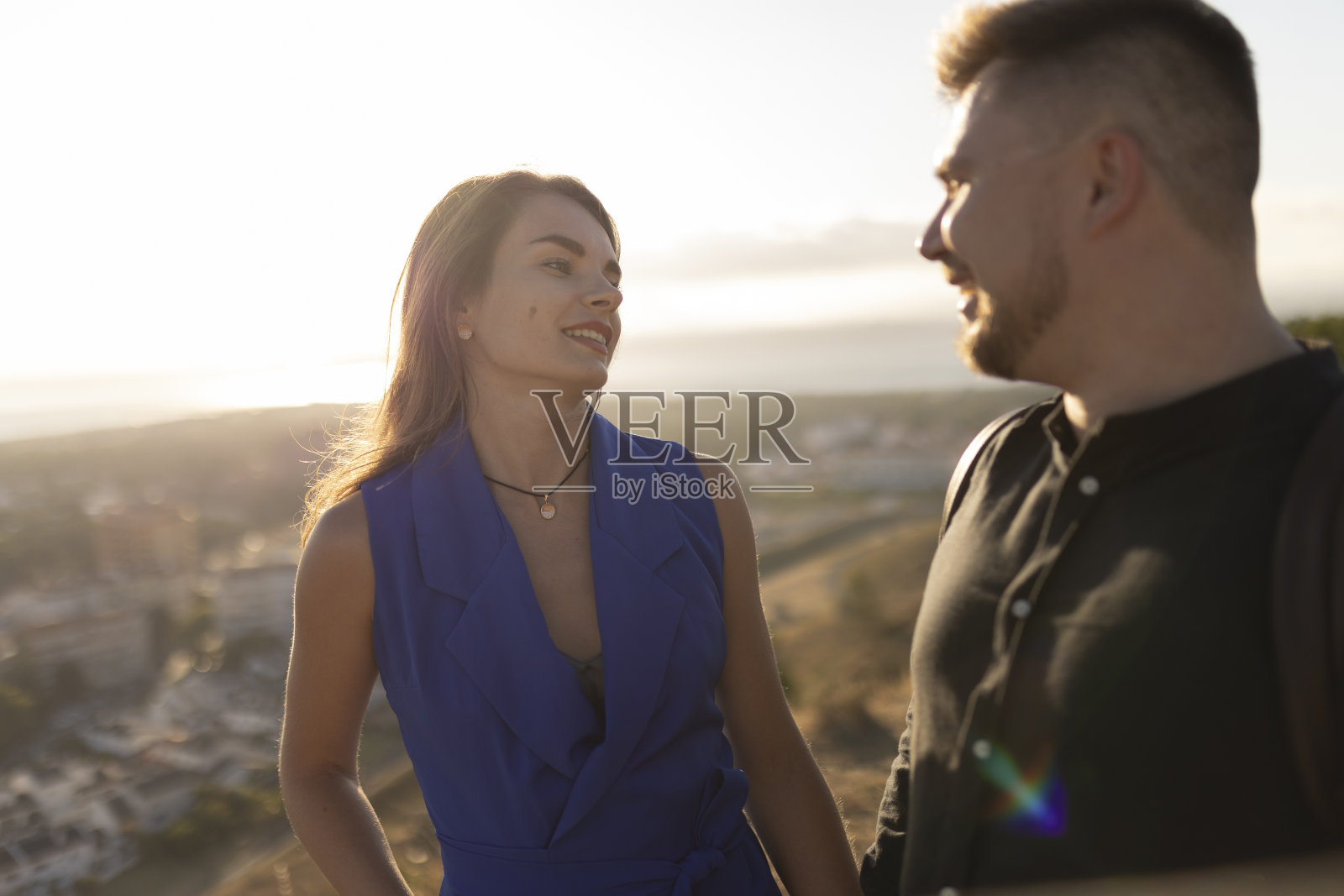 年轻的夫妇聊天，欣赏日落的城市景观照片摄影图片