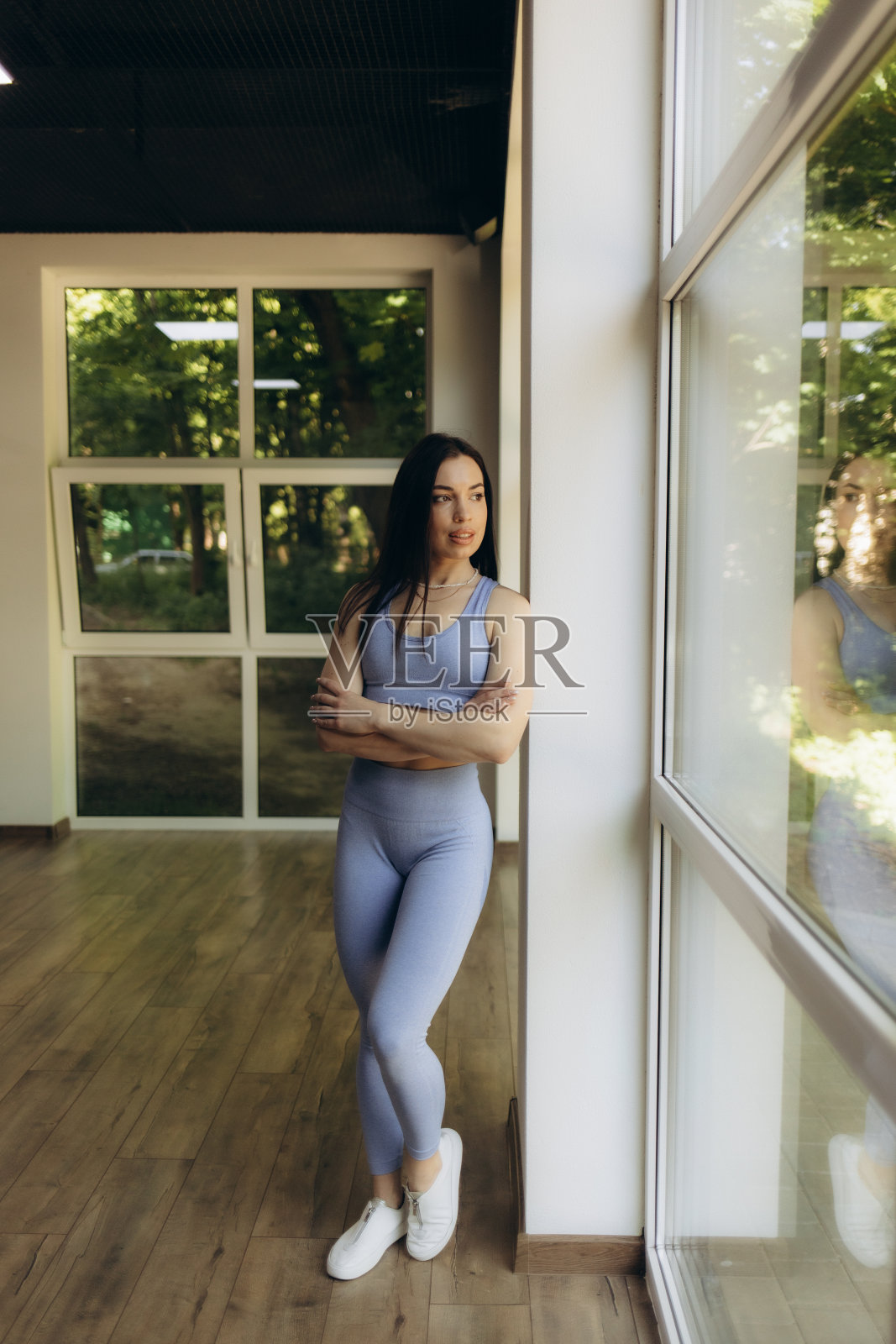 身穿运动服的年轻女性在健身房弯腰，双手放在膝盖上。健身女性在剧烈的综合健身锻炼后看起来很累。照片摄影图片