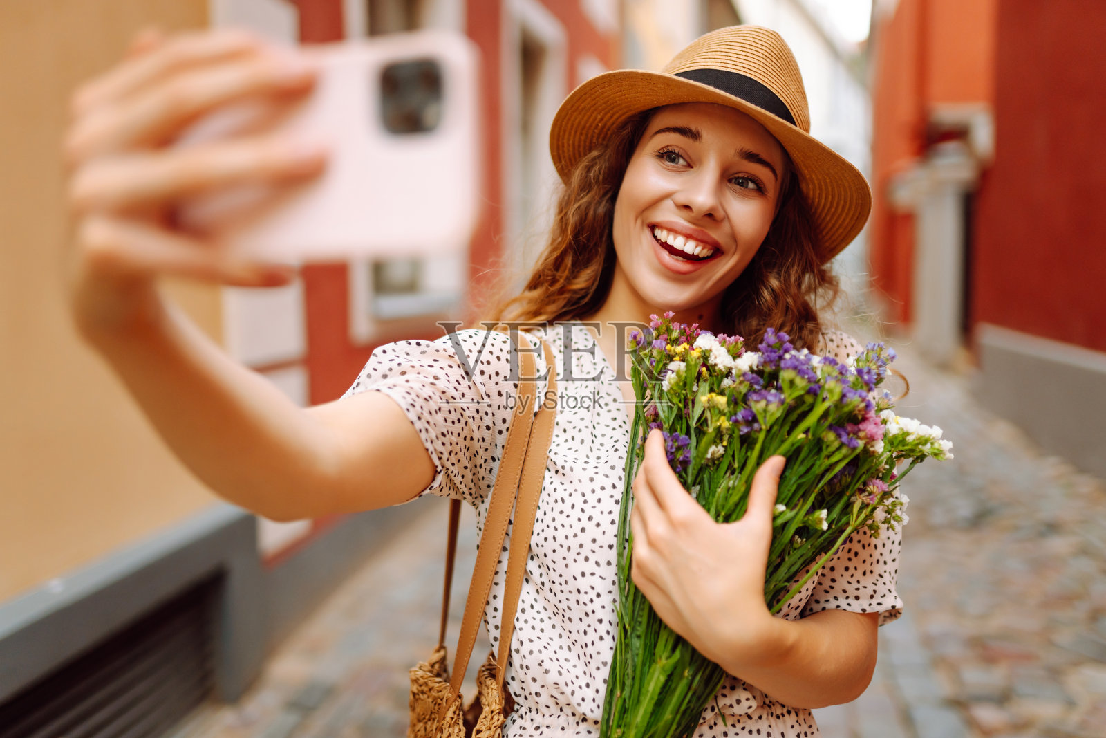 有问题的时间。手持一束野花的年轻女子在街上摆姿势。照片摄影图片