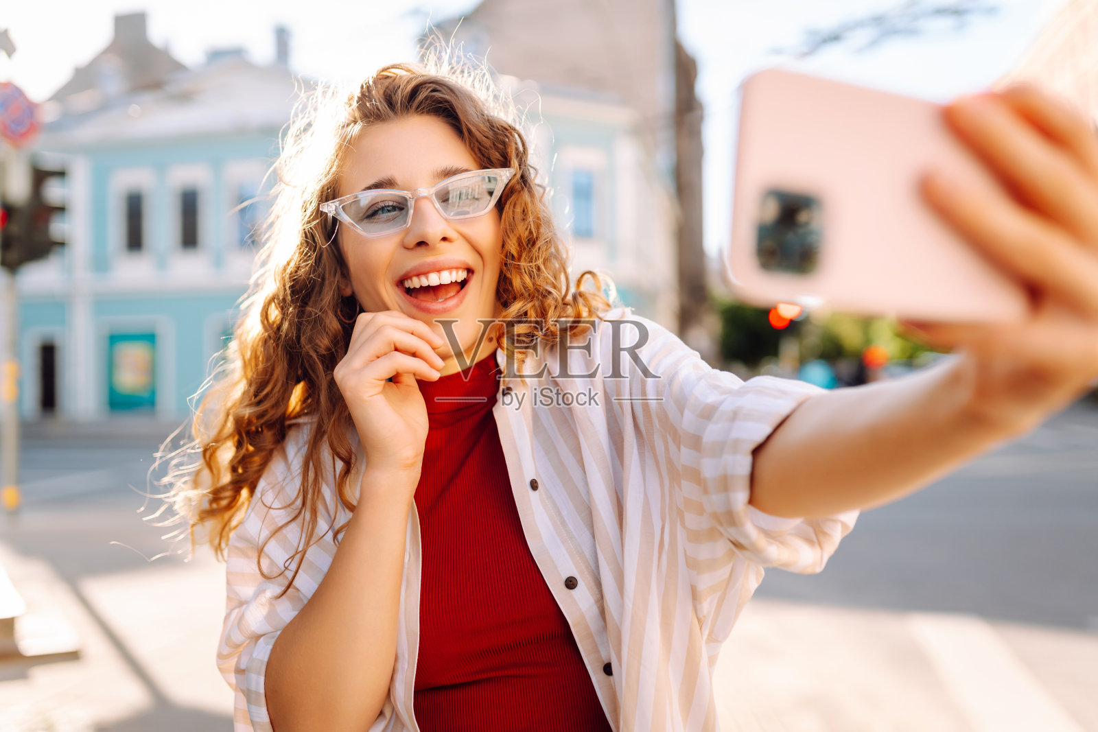 年轻女子走在街上，用智能手机自拍。照片摄影图片