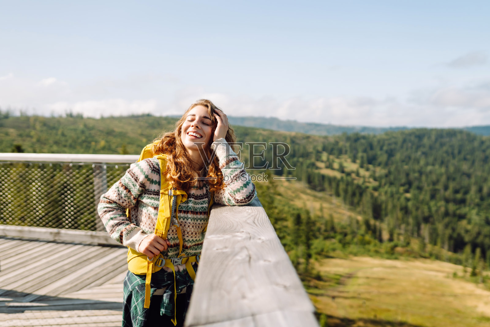 年轻女子在山顶的观景台上欣赏美丽的自然景色。照片摄影图片
