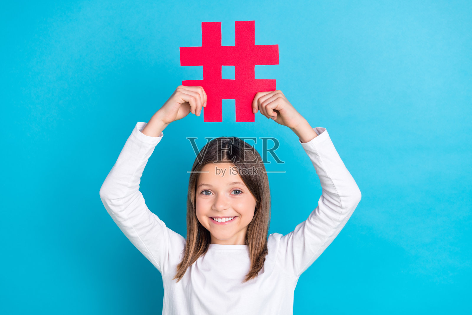 可爱的女学生，直发，穿着白衬衫，蓝色背景上有标签图标照片摄影图片