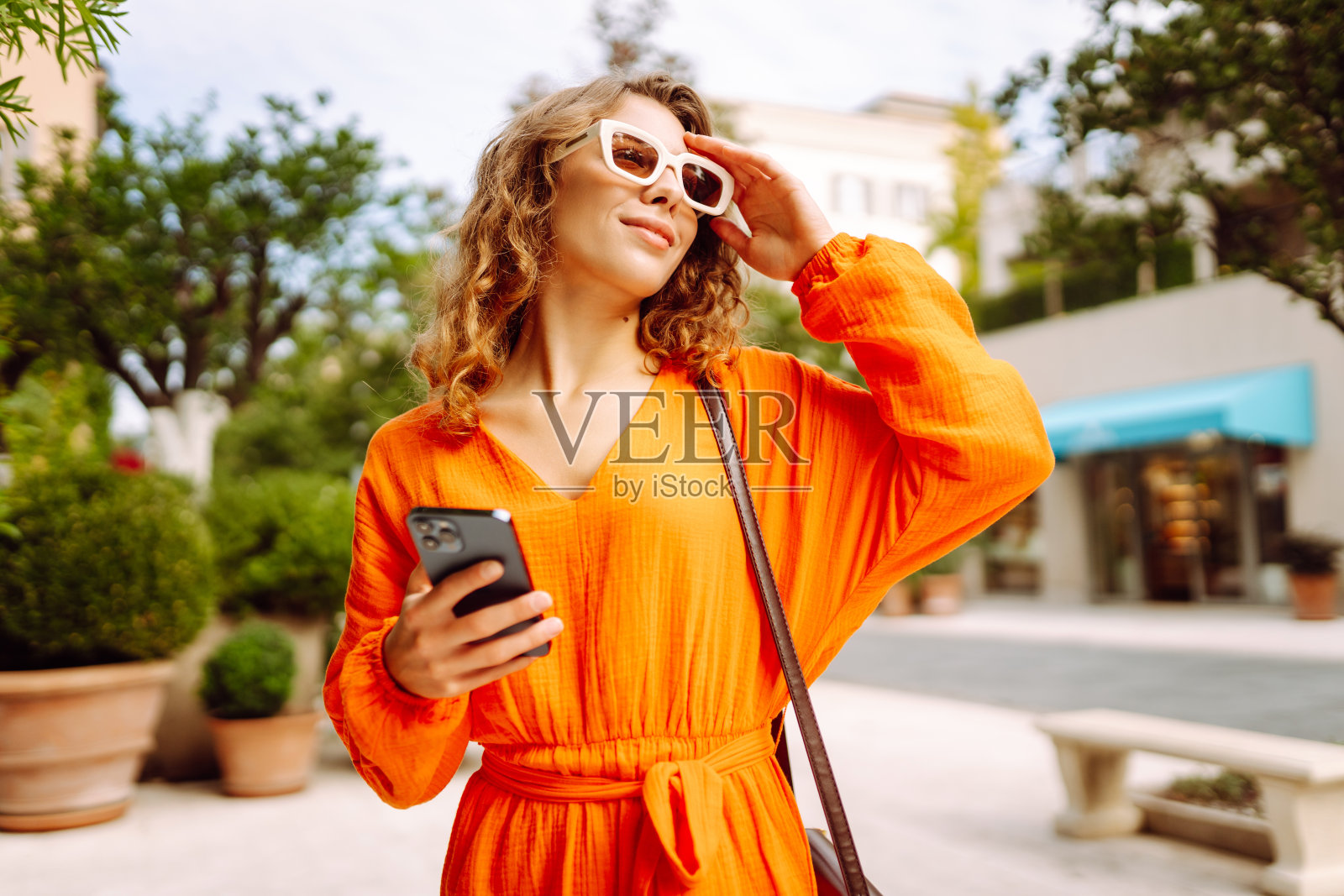 年轻女游客走在城市街道上使用智能手机。照片摄影图片