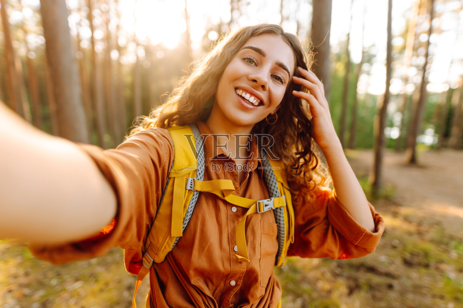 快乐的女游客在阳光明媚的森林里散步时给自己拍照。照片摄影图片