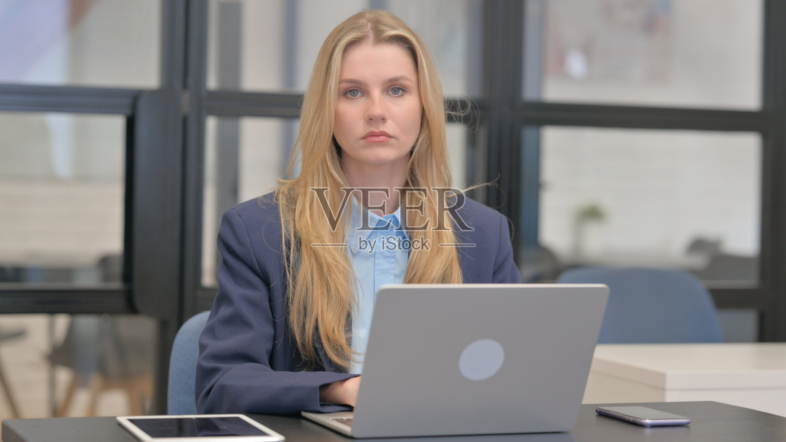 年轻的女商人一边用笔记本电脑工作，一边看着相机照片摄影图片