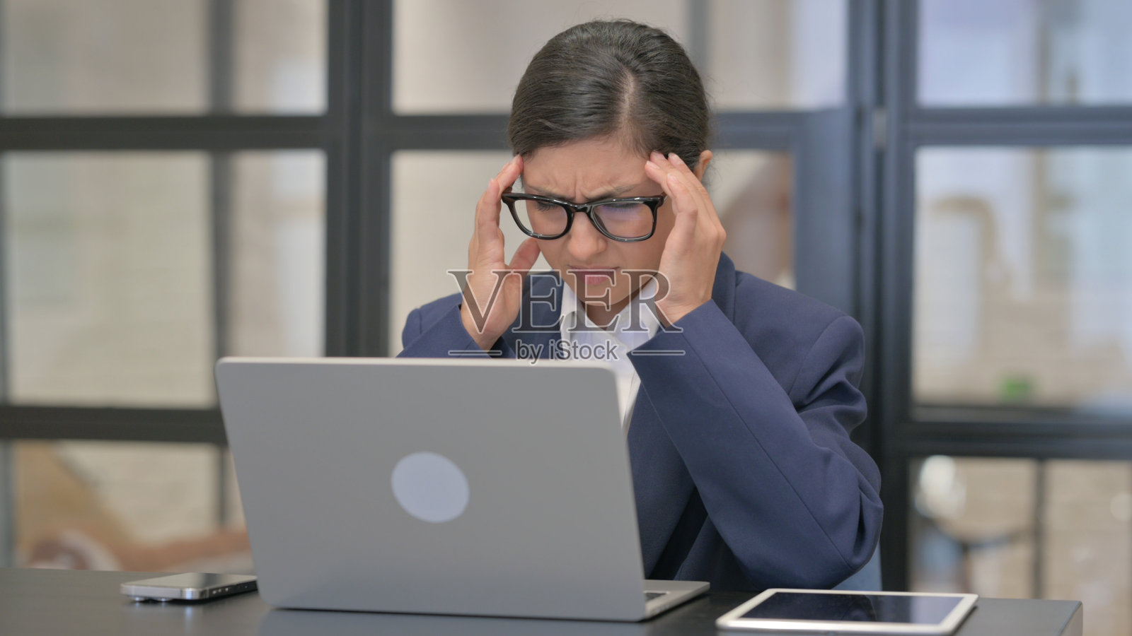 患有偏头痛的混血女商人在办公室工作照片摄影图片