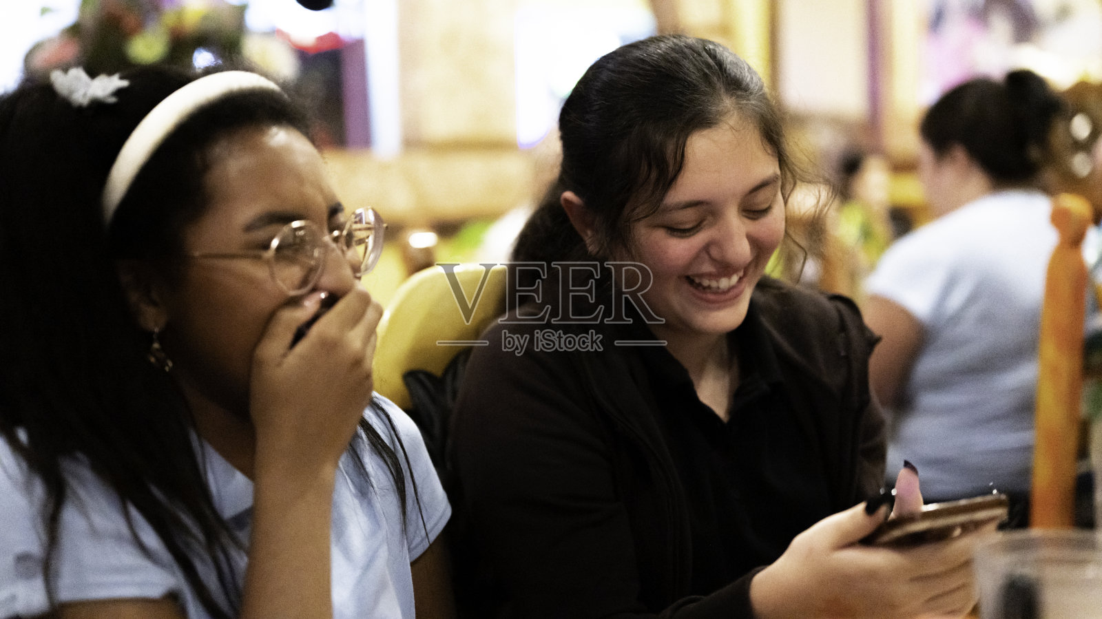 两个青春期前的初中女生朋友在学校食堂一起快乐地使用手机照片摄影图片
