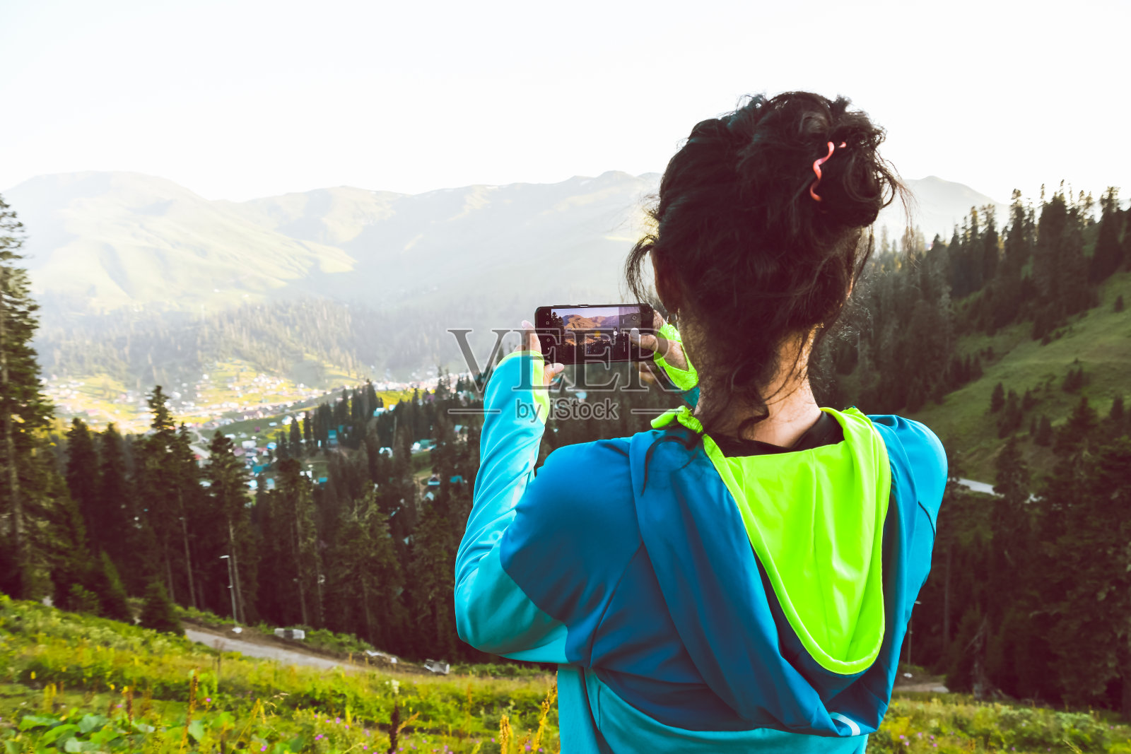 时髦女孩一边用手机拍摄美丽日出的视频照片，一边用复制空间站在明亮的天空景色背景下。女游客正在用手机拍照照片摄影图片