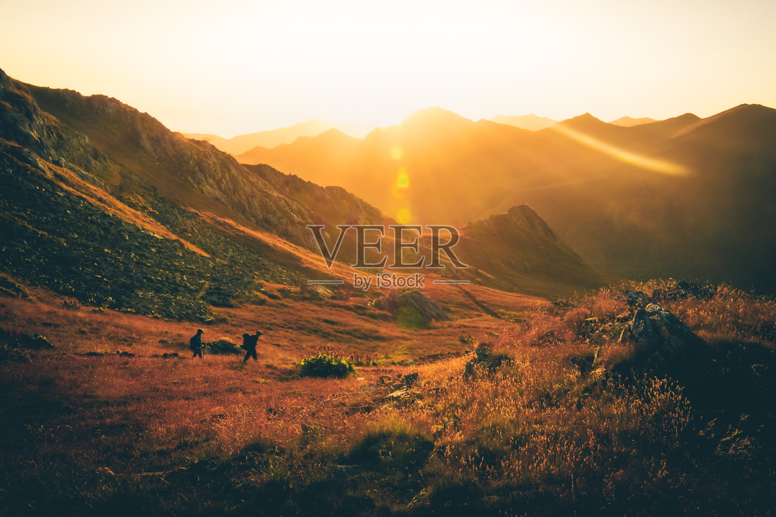 两个徒步旅行的朋友在美丽的秋天日落一起在户外的小路左边徒步旅行。活跃的人们在高加索山脉徒步旅行照片摄影图片