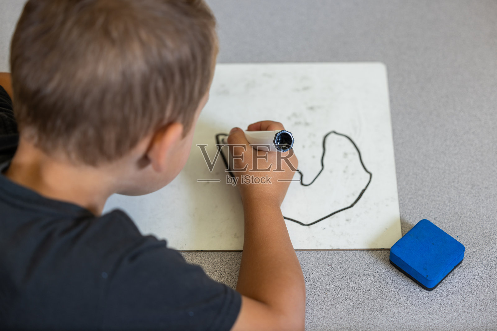 一个男孩正在用记号笔在白板上画画照片摄影图片