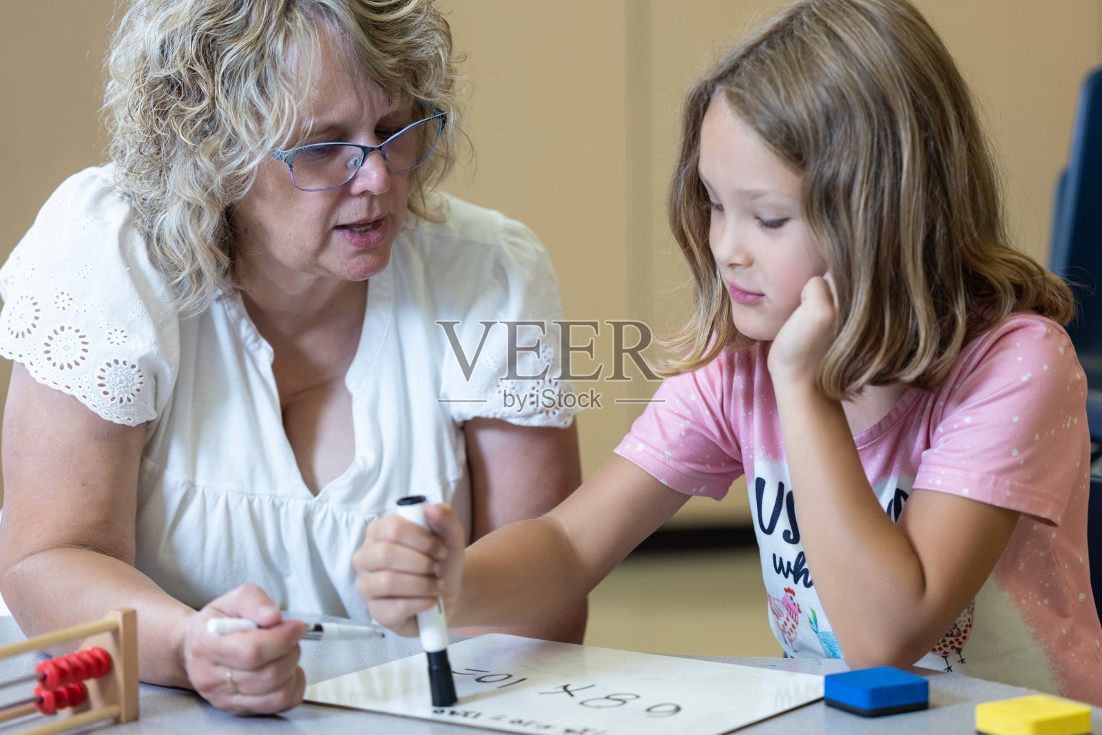 一位老师正在帮助一个小女孩做数学作业照片摄影图片