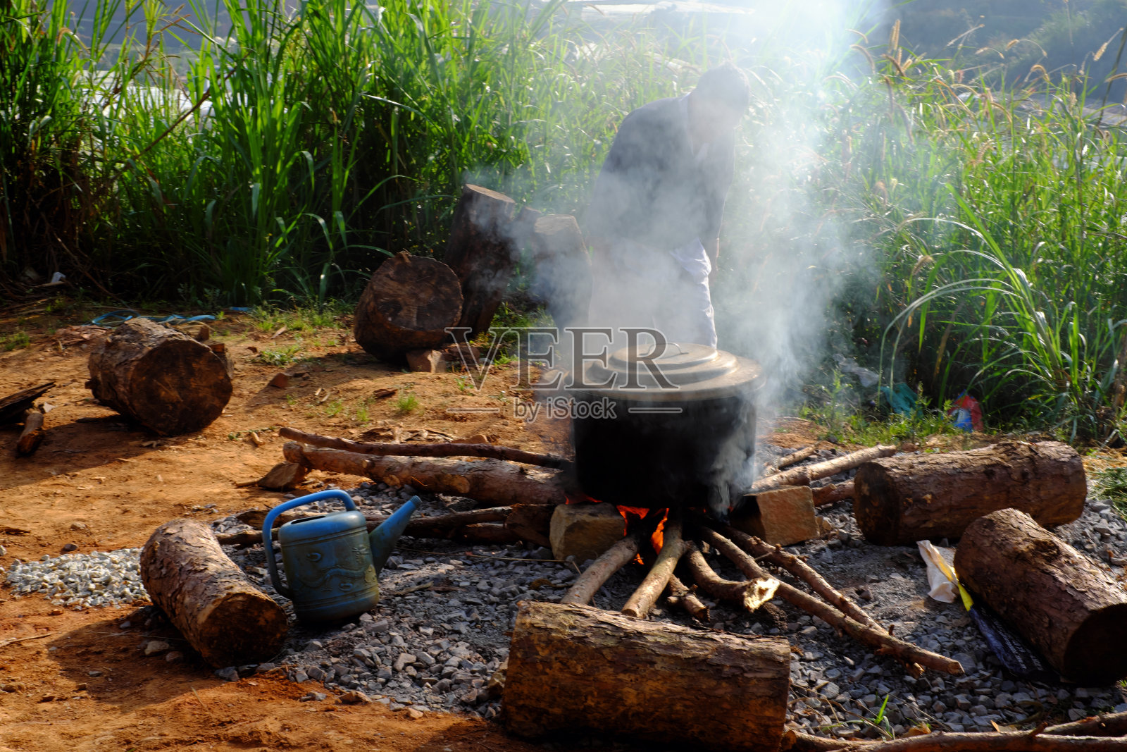 在户外，在砖块和石头搭建的临时炉子上的明火上冒着热气的黑锅，周围环绕着大自然，作为越南传统的春节烹饪banhtet是一种文化美食照片摄影图片