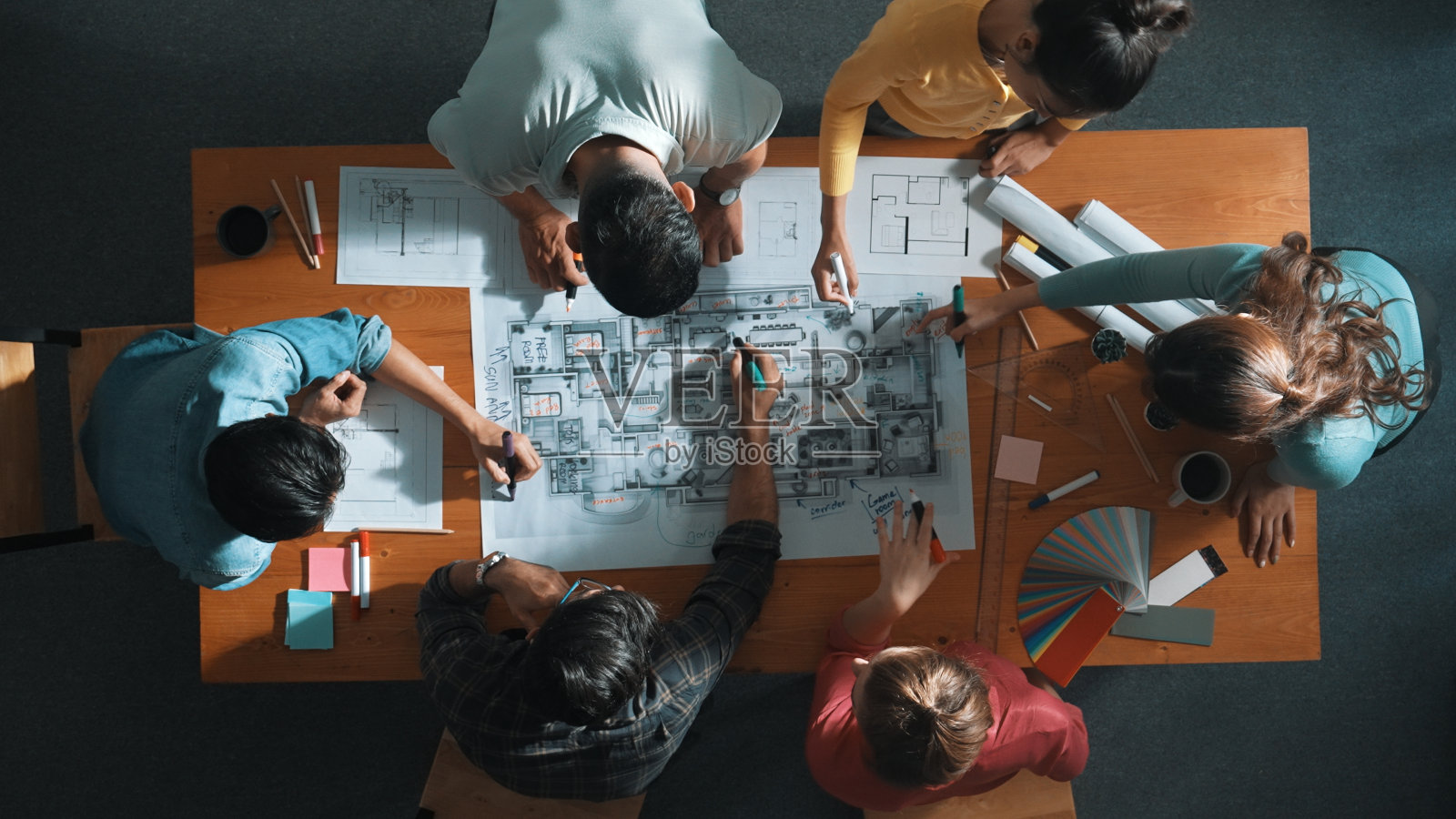 工程师团队在会议桌上撰写蓝图的自顶向下视图。研讨会。照片摄影图片