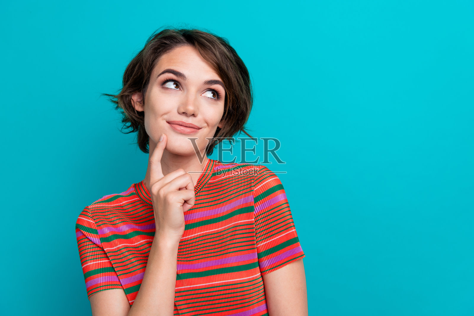 聪明女孩的肖像，短发，穿着时尚的t恤，梦幻的样子，在蓝绿色的背景上提供孤立的空间照片摄影图片