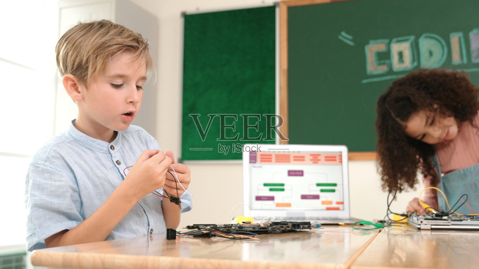 女孩站着用螺丝刀固定电路板。教育学。照片摄影图片