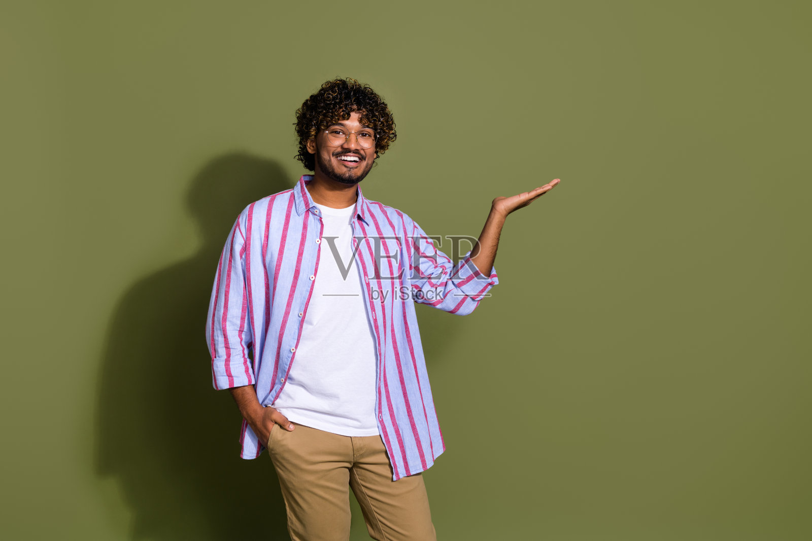 肖像照片英俊的阿拉伯商人在条纹休闲衬衫和眼镜持有产品孤立的卡其色背景照片摄影图片