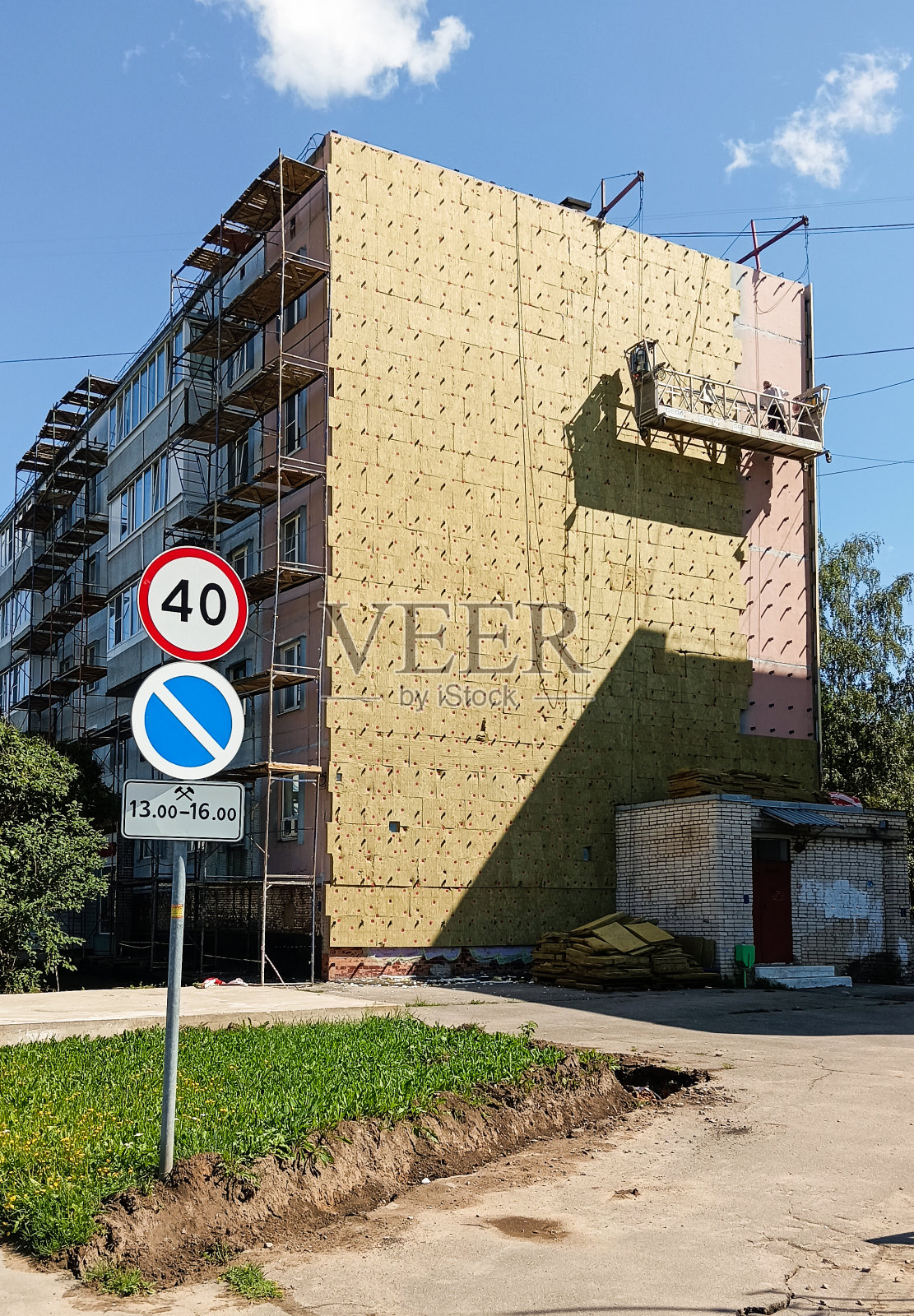 在摇篮里工作的工人正在修理这座建筑物。照片摄影图片