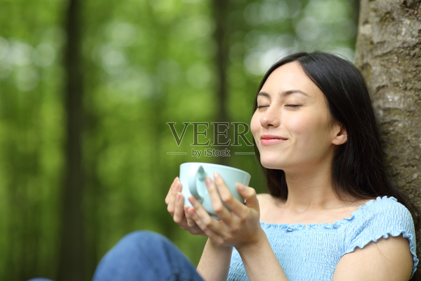 一个亚洲女人在公园里喝咖啡照片摄影图片