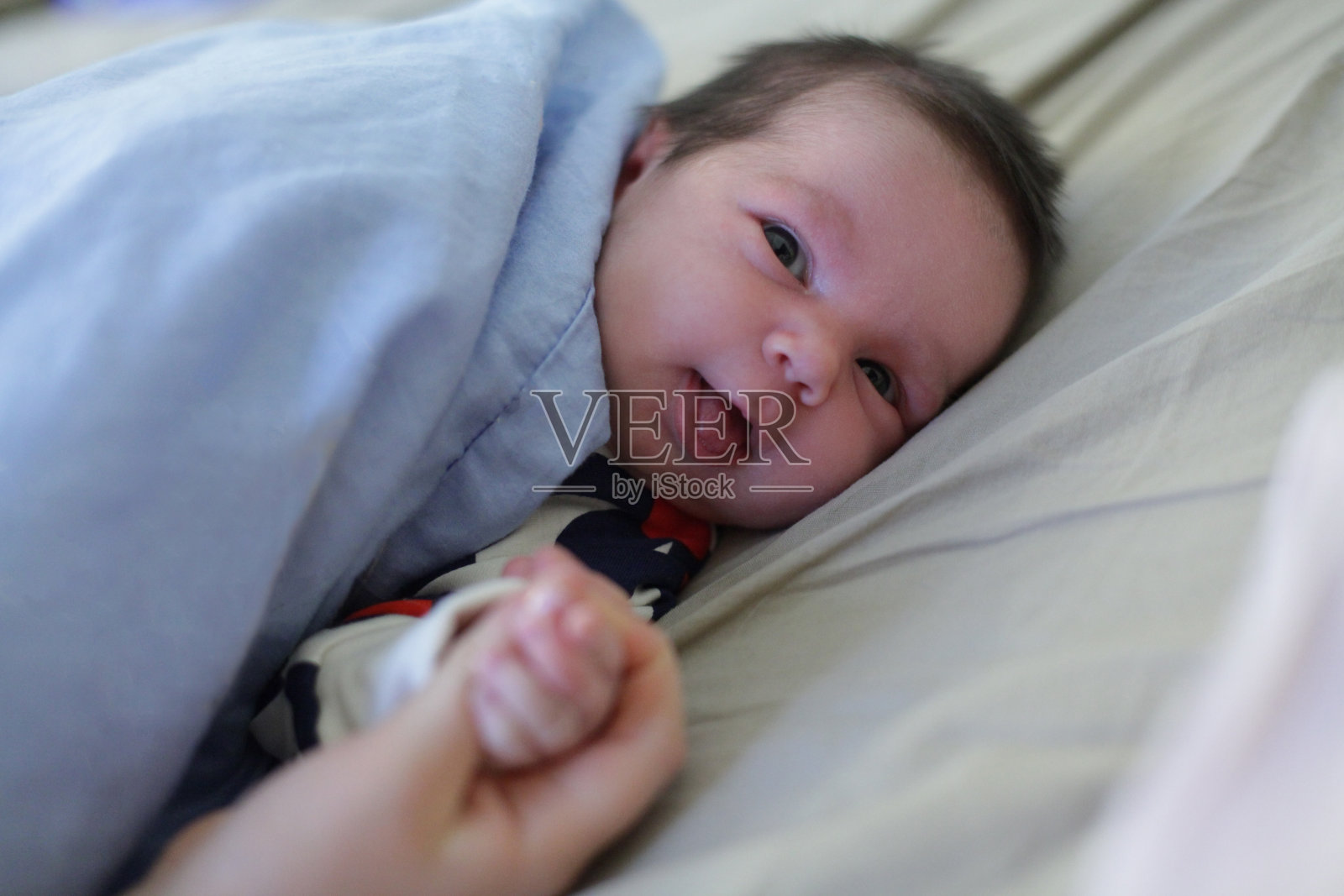 母亲抚摸家中熟睡的新生儿的手(特写)照片摄影图片