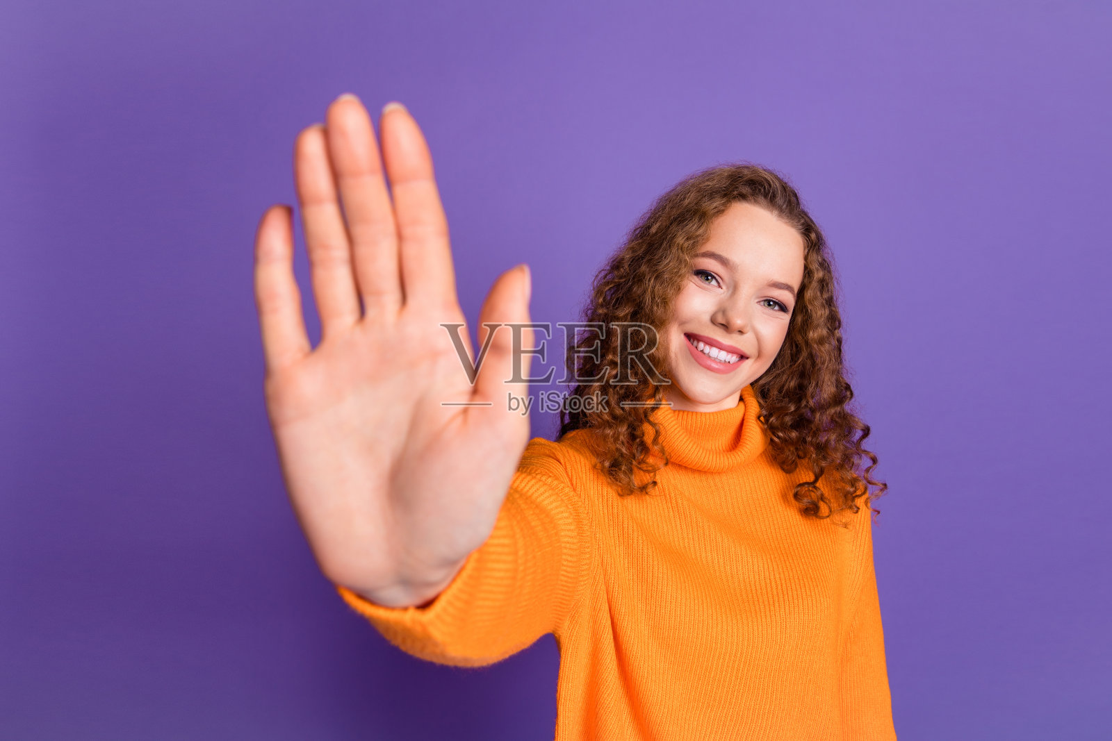 照片可爱的年轻女孩手臂手掌波hi穿毛衣孤立的紫罗兰色背景照片摄影图片
