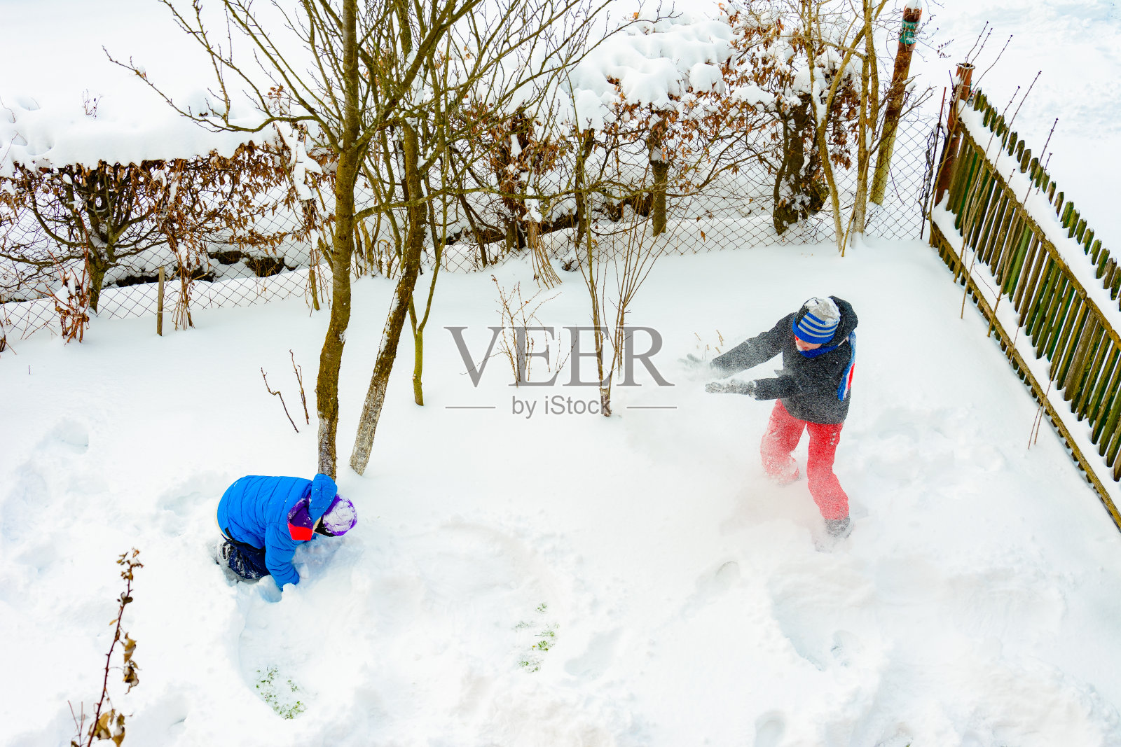 两兄弟在他们家附近打雪仗。照片摄影图片