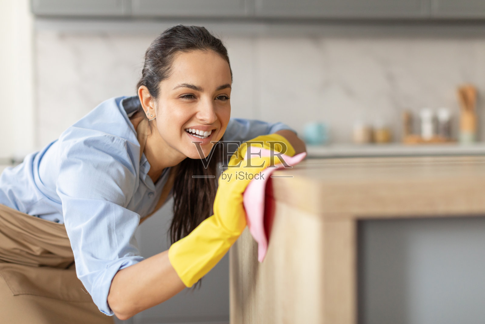 在厨房里擦拭家具的微笑女人，留白照片摄影图片