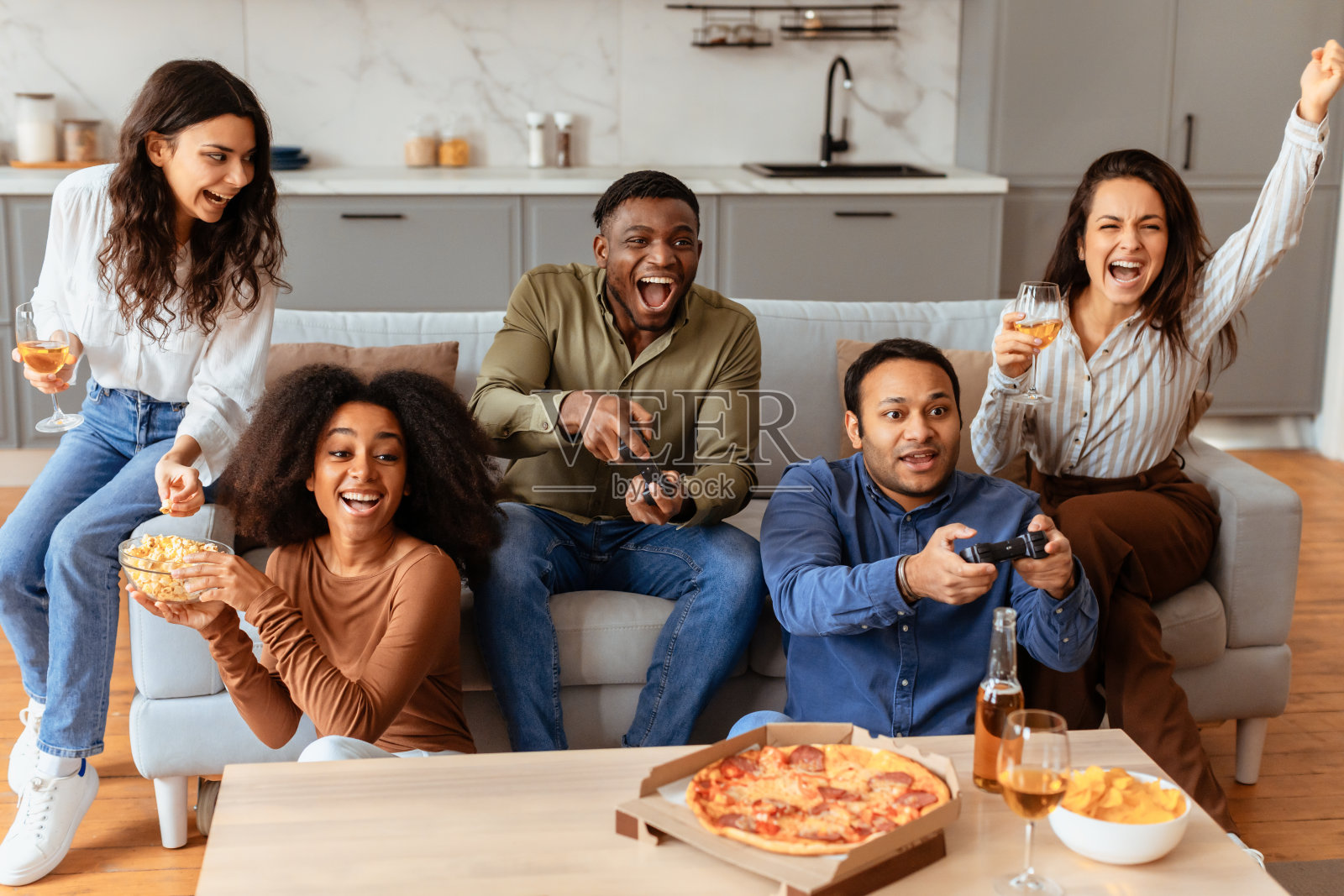 朋友们在沙发上玩电子游戏和吃零食照片摄影图片