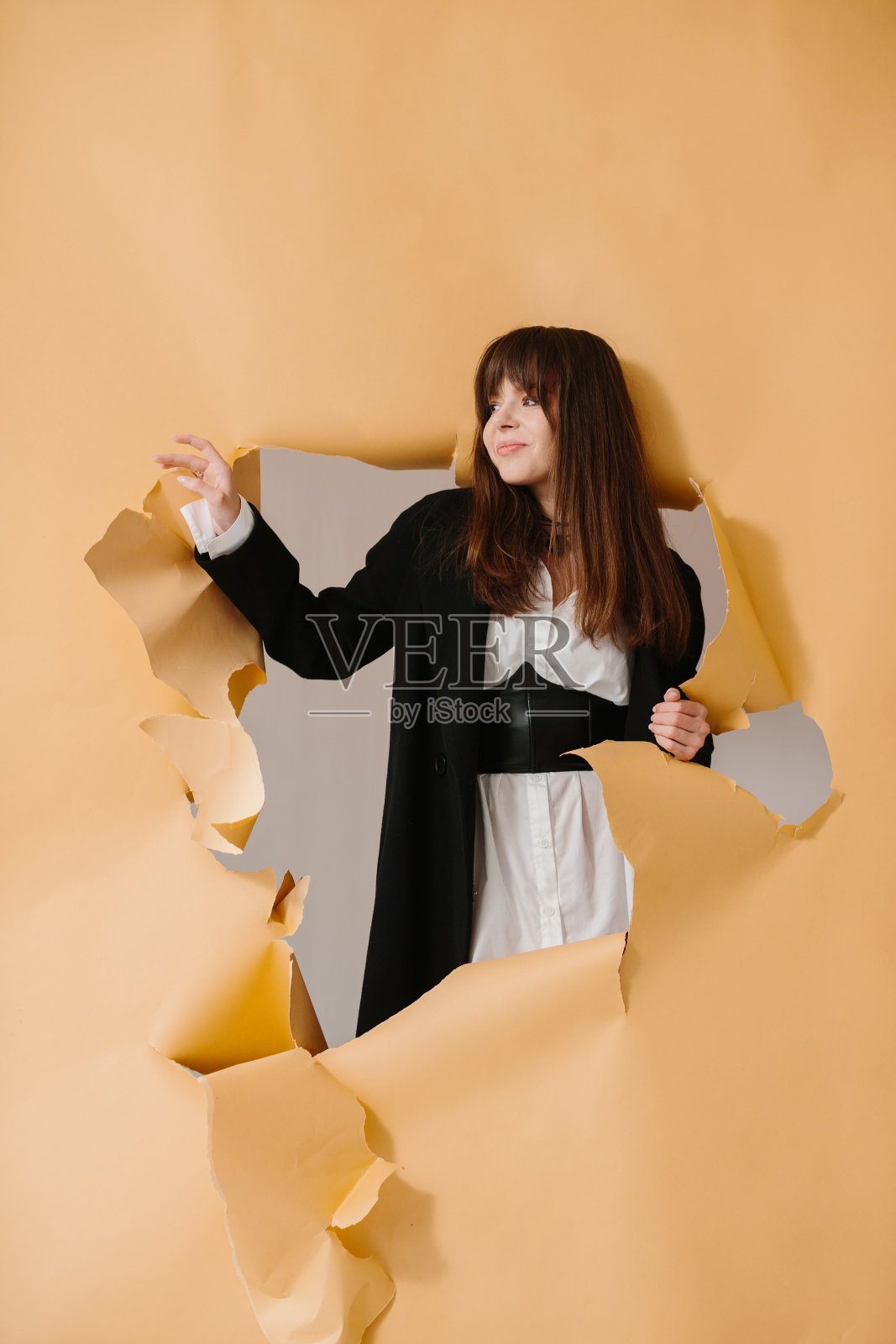 时尚和风格的概念。年轻漂亮的女孩在工作室里以破纸为背景摆姿势。照片摄影图片