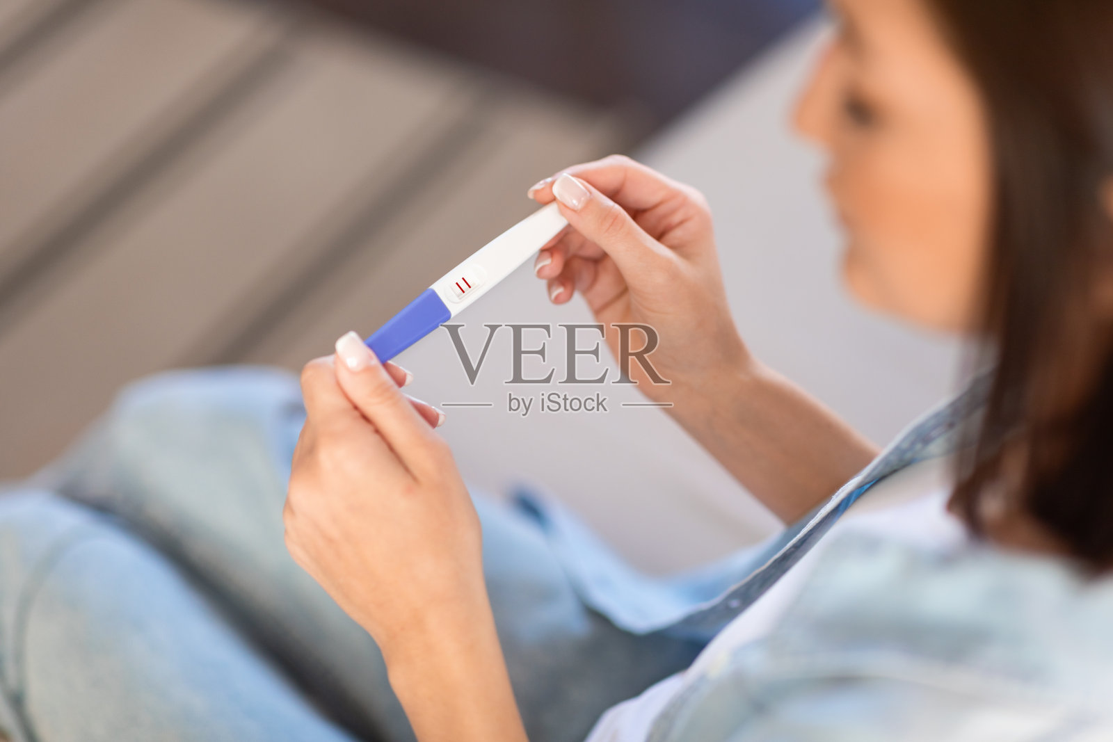 不认识的年轻女士在家里看着怀孕测试呈阳性照片摄影图片