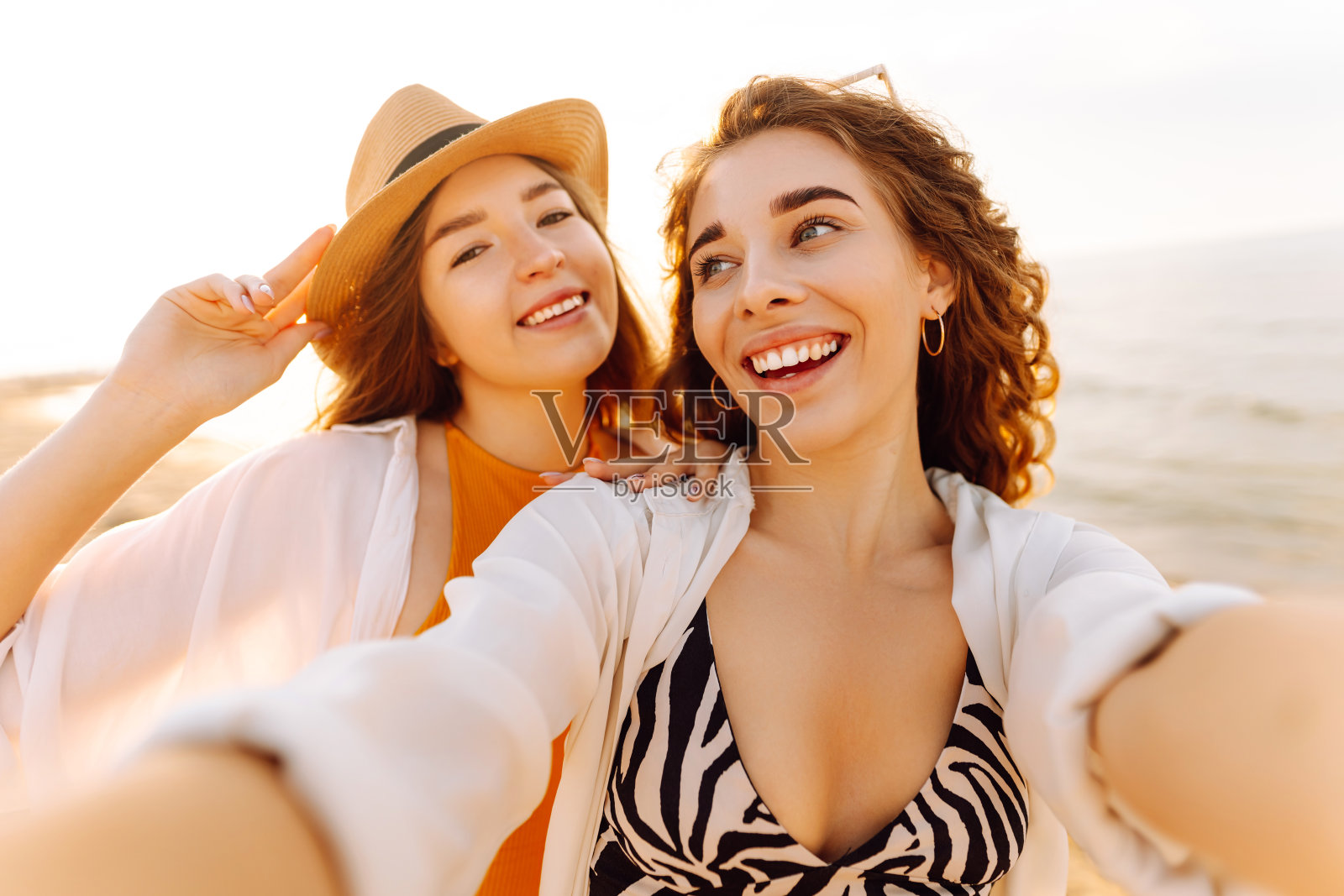 两个漂亮的闺蜜在沙滩上自拍，夏日的色彩轻盈明亮。照片摄影图片