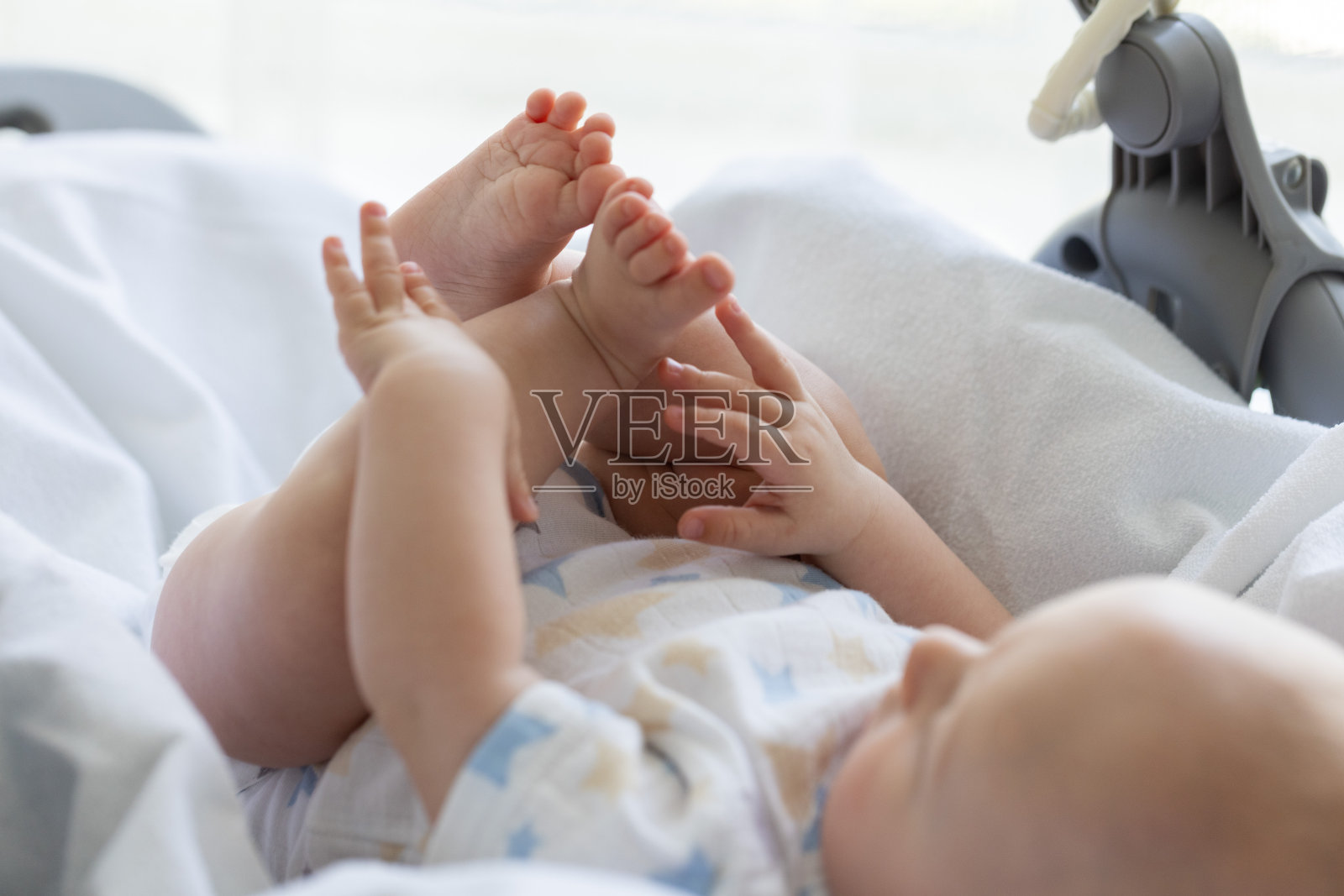 刚出生的婴儿想摸他的脚。照片摄影图片